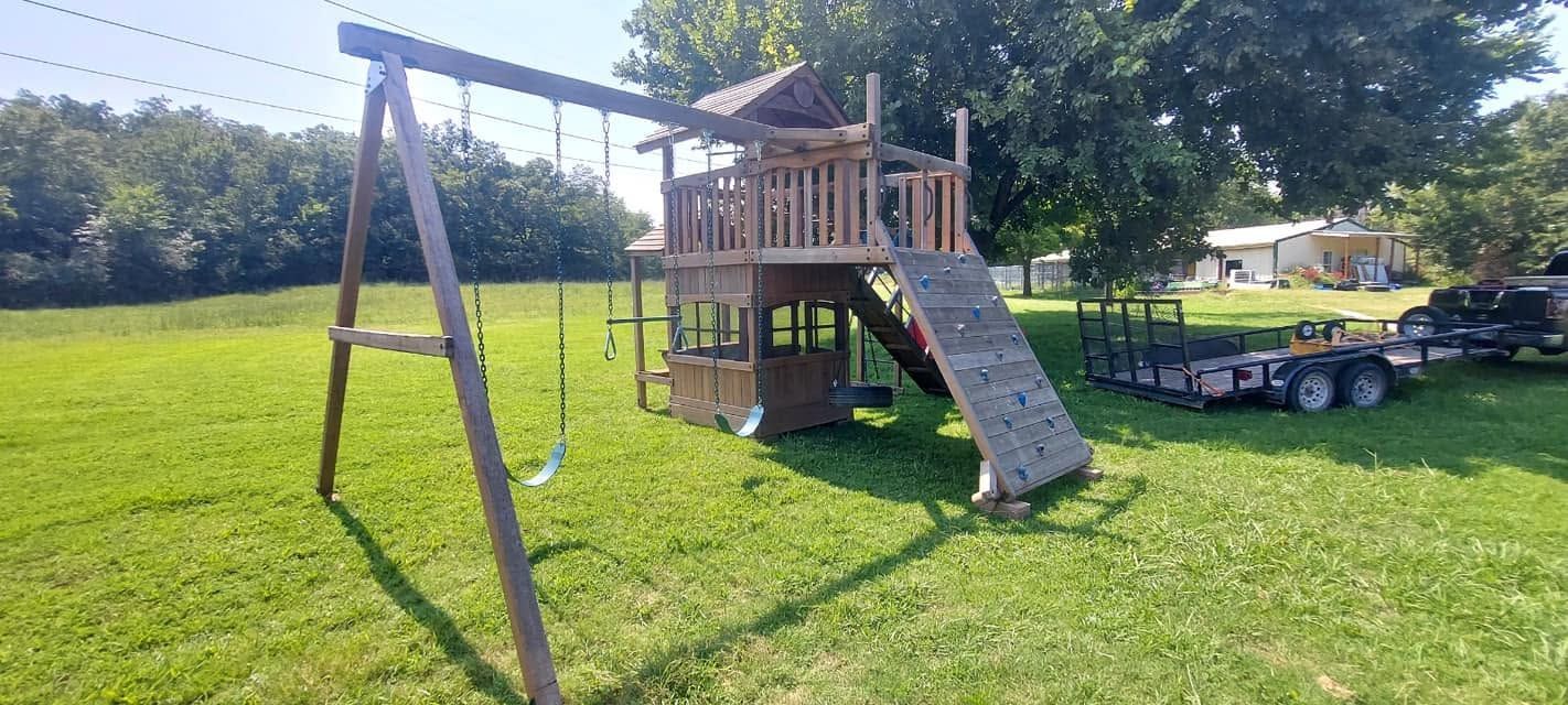 Backyard playset with swings, slide, and wooden deck on a grassy lawn