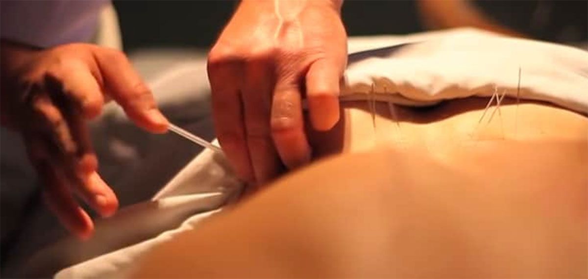 Hands adjusting a white sheet on a person&rsquo;s back during a massage or therapy session