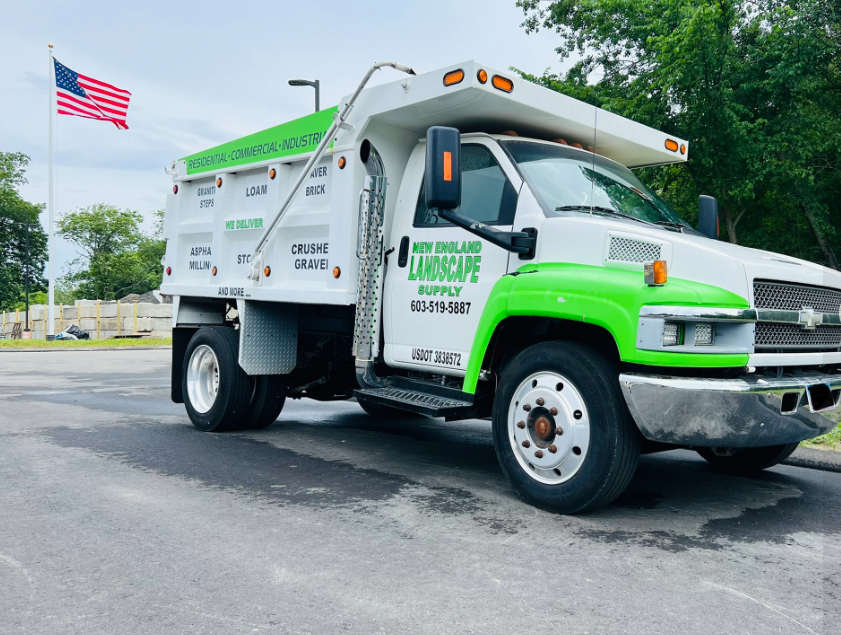 A white and green truck is parked in a parking lot