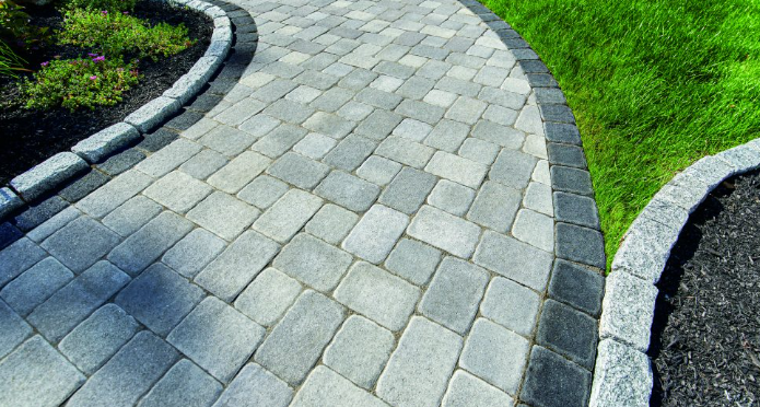 A brick walkway leading to a lush green lawn.