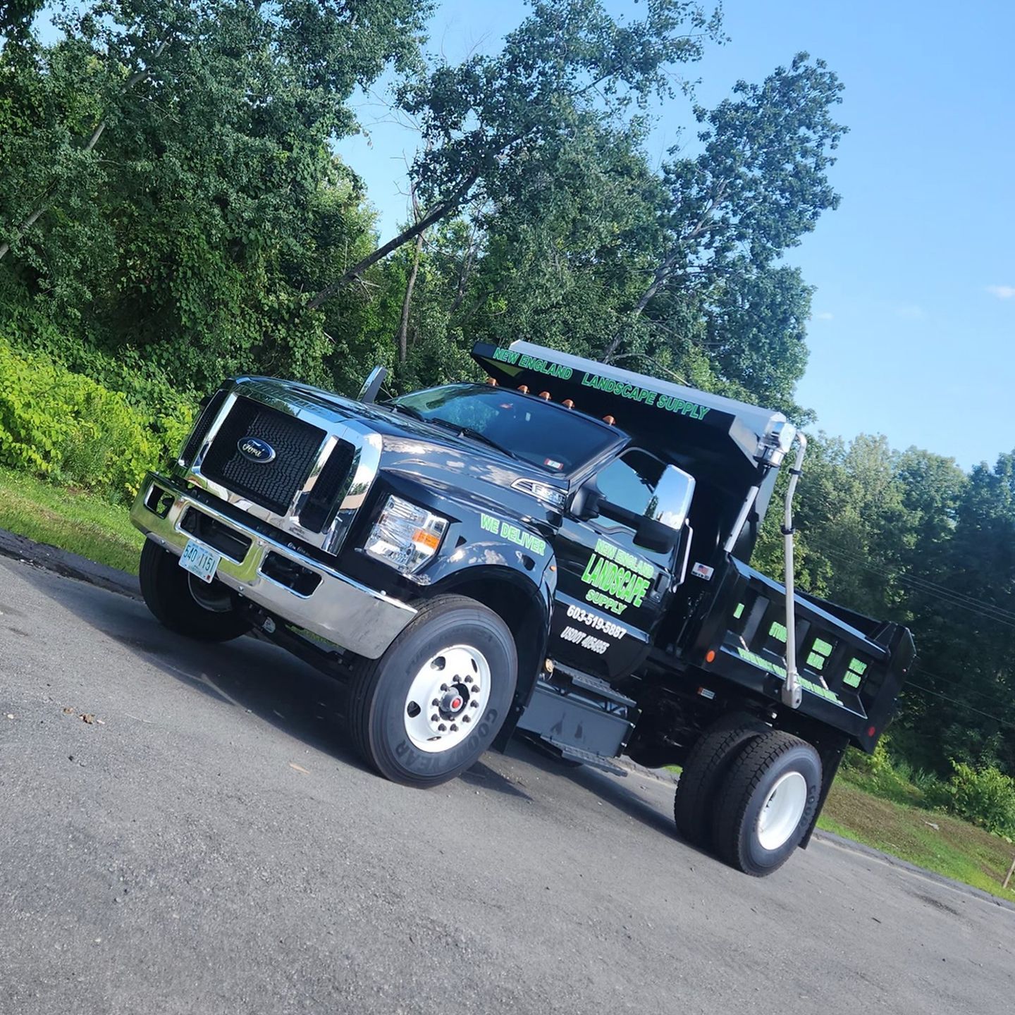 A black dump truck is parked on the side of the road.