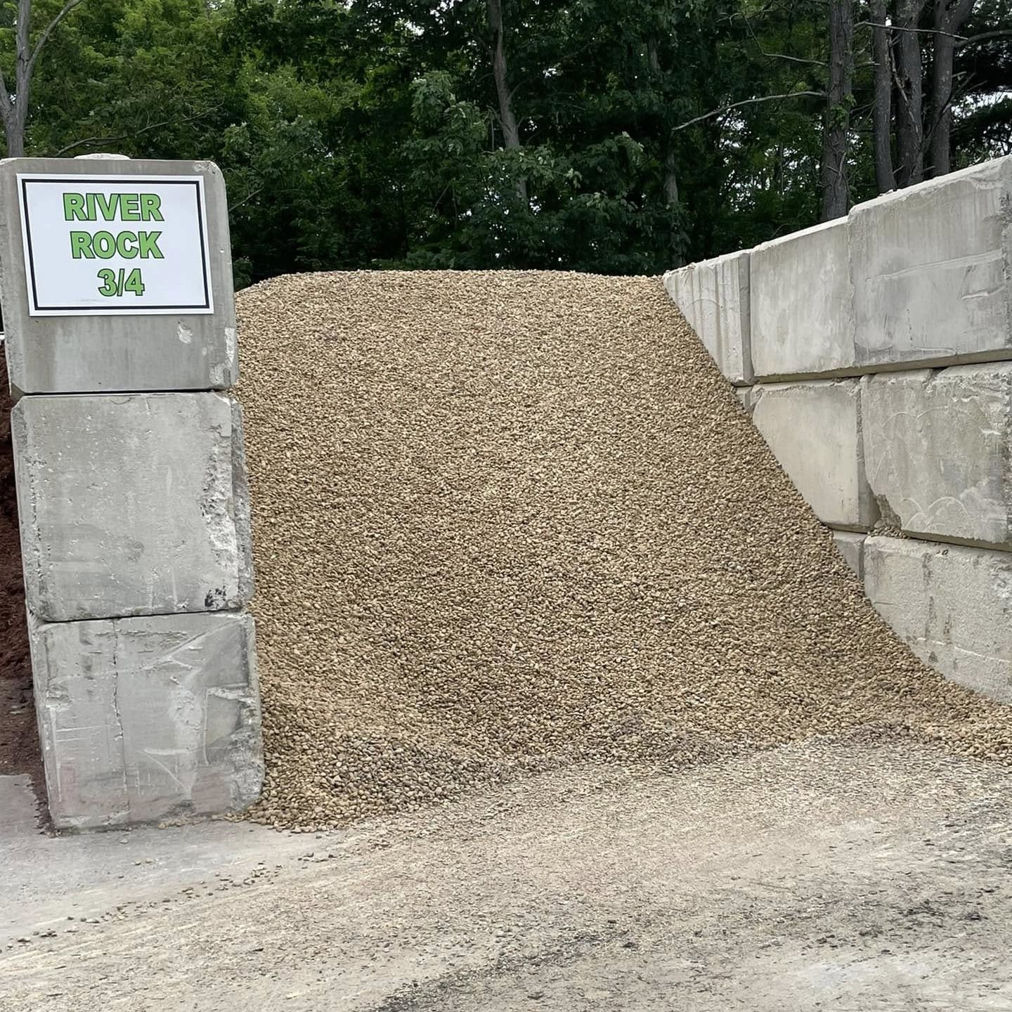 A pile of gravel is sitting next to a concrete block.