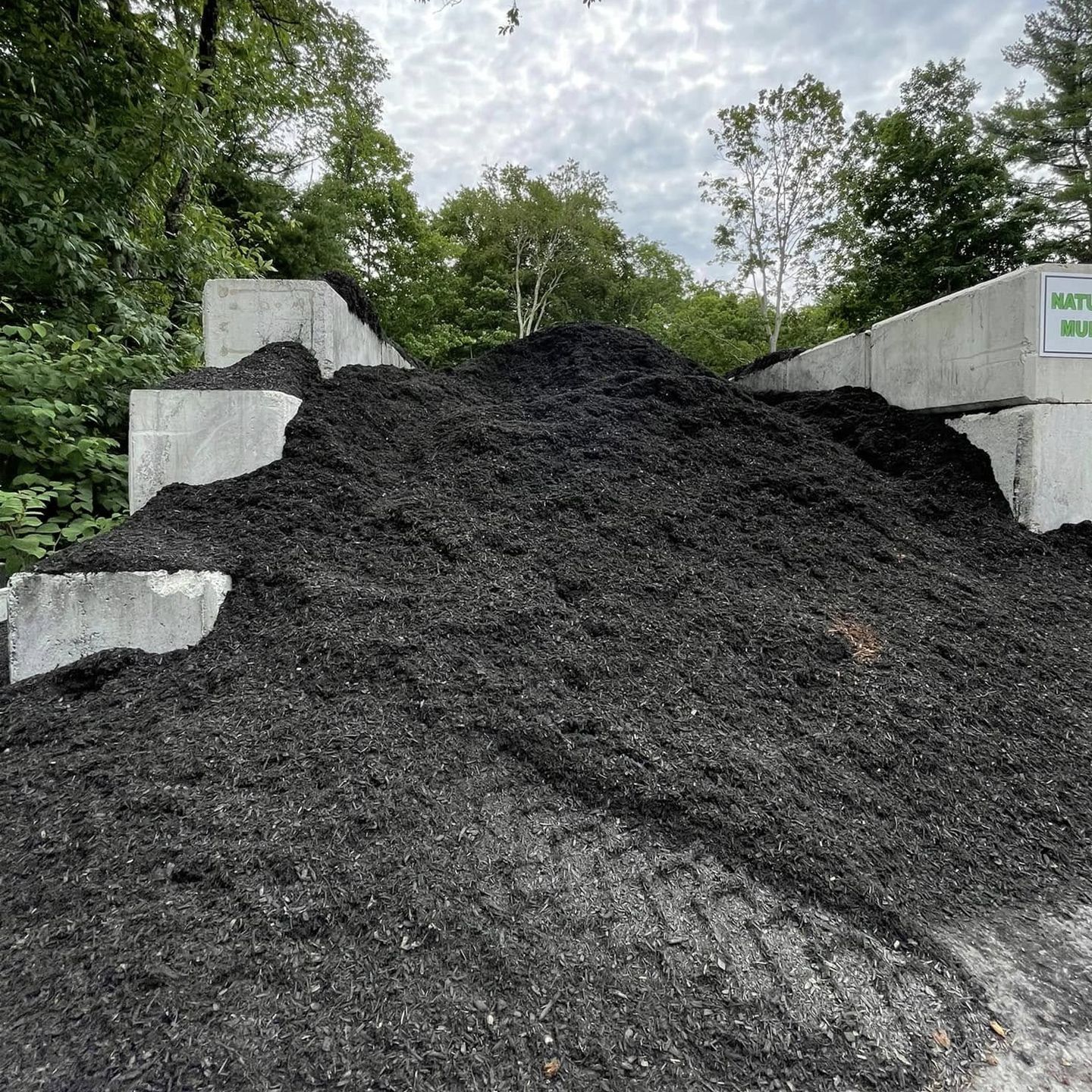 A pile of brown mulch is sitting on the side of a road.