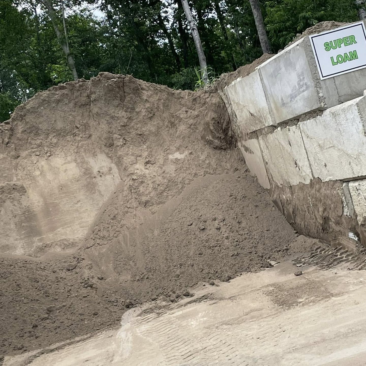 A pile of dirt is sitting next to a concrete block.