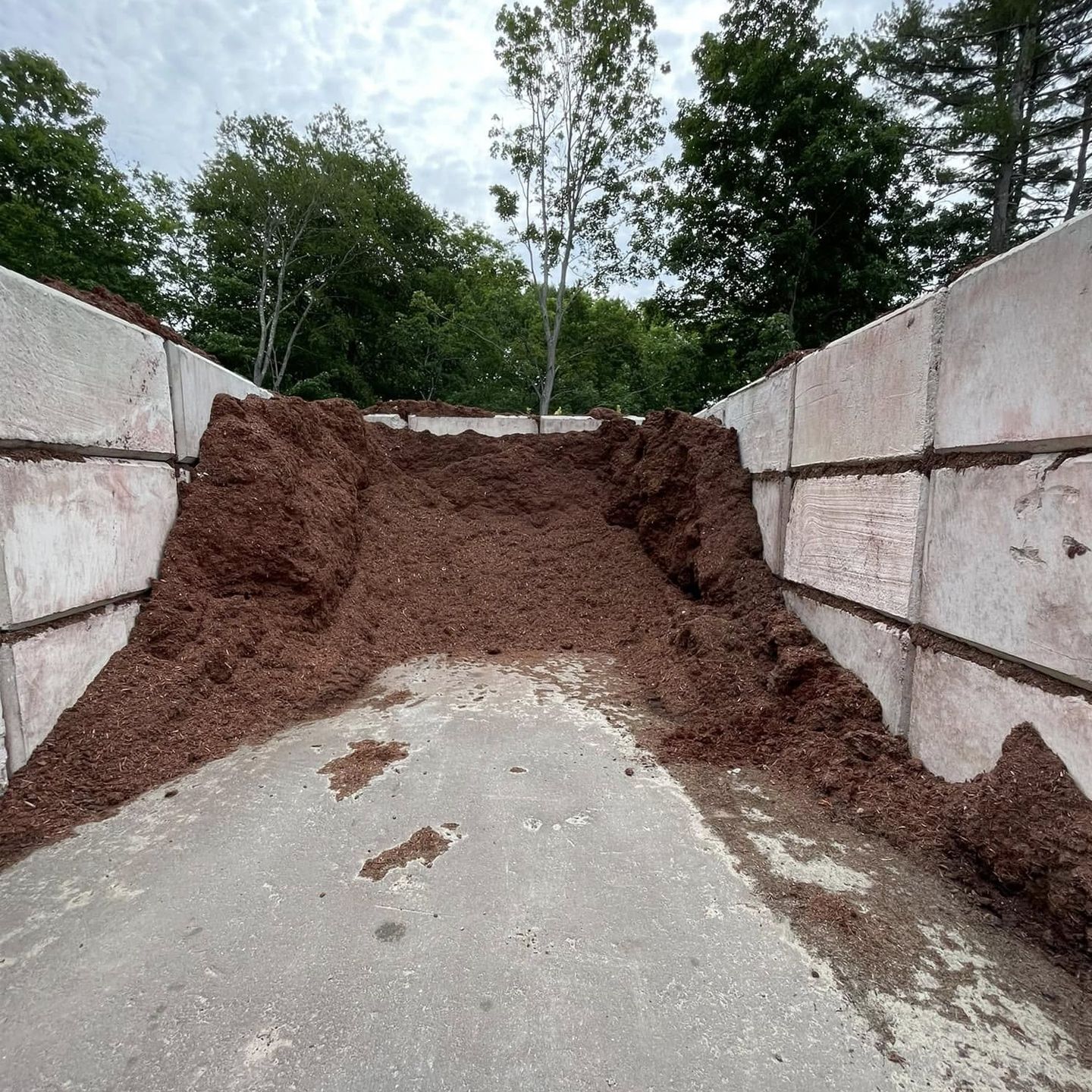 A pile of brown mulch is sitting on the side of a road.