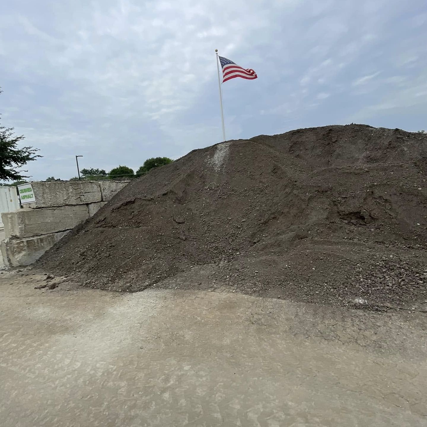 An american flag is flying over a pile of dirt.