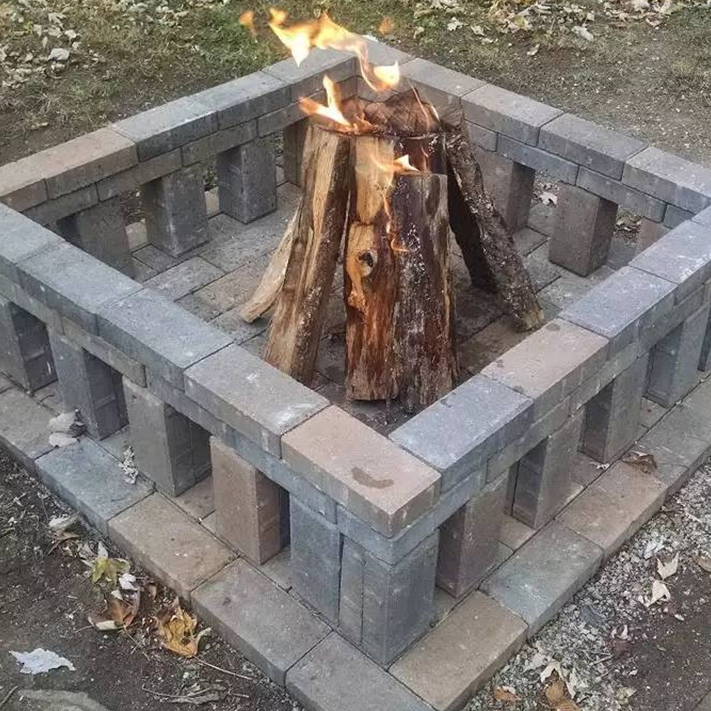 A fire pit made out of bricks with a log in it.