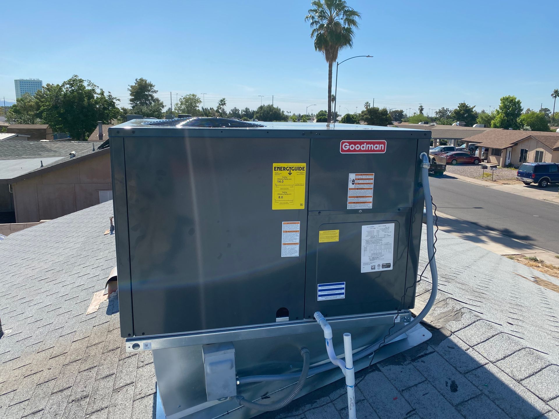 A large black box is sitting on top of a roof next to a palm tree.