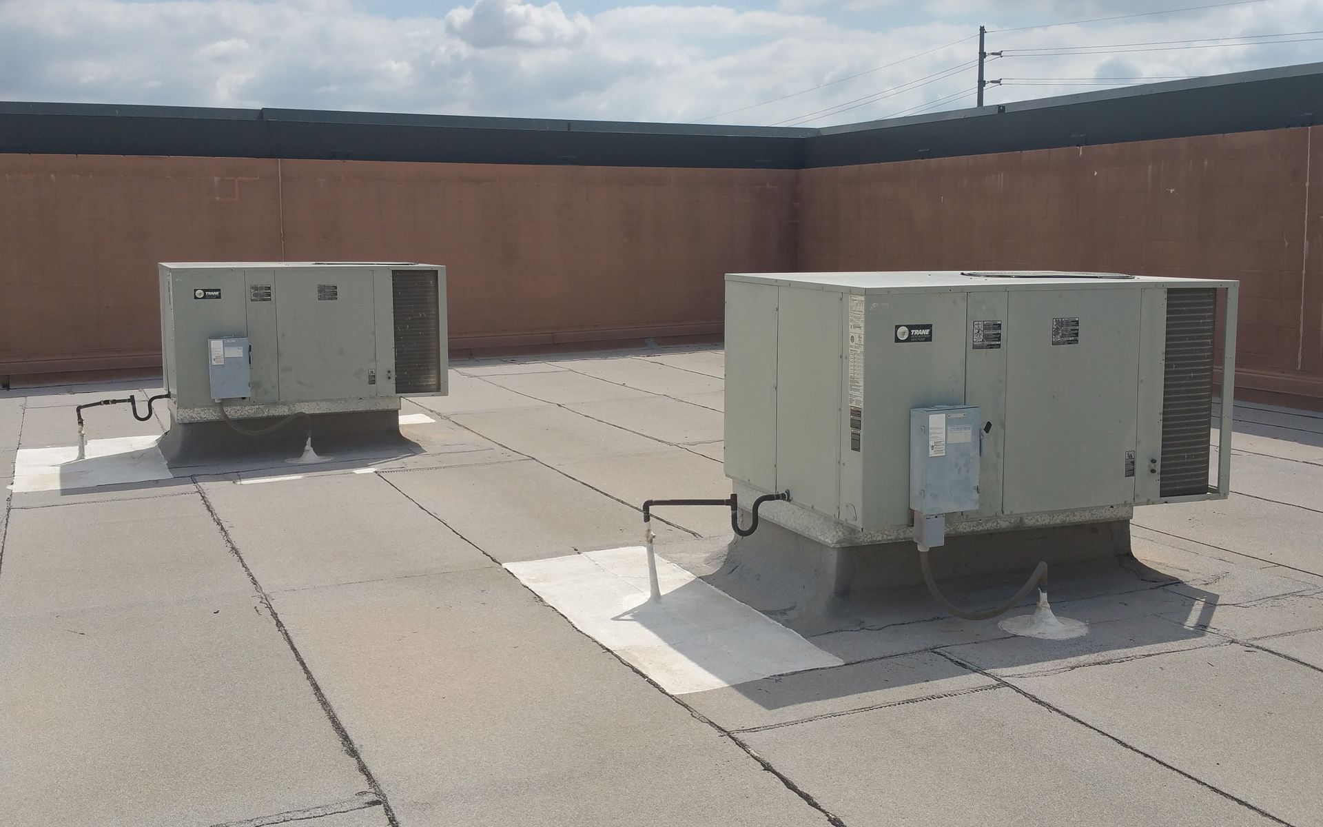 Two air conditioners are sitting on top of a roof.