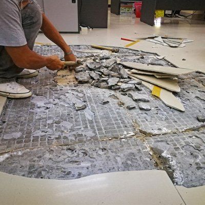 A man is working on a broken tile floor