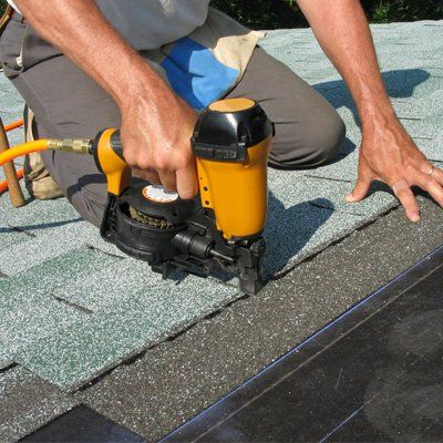 man working on roof shingles