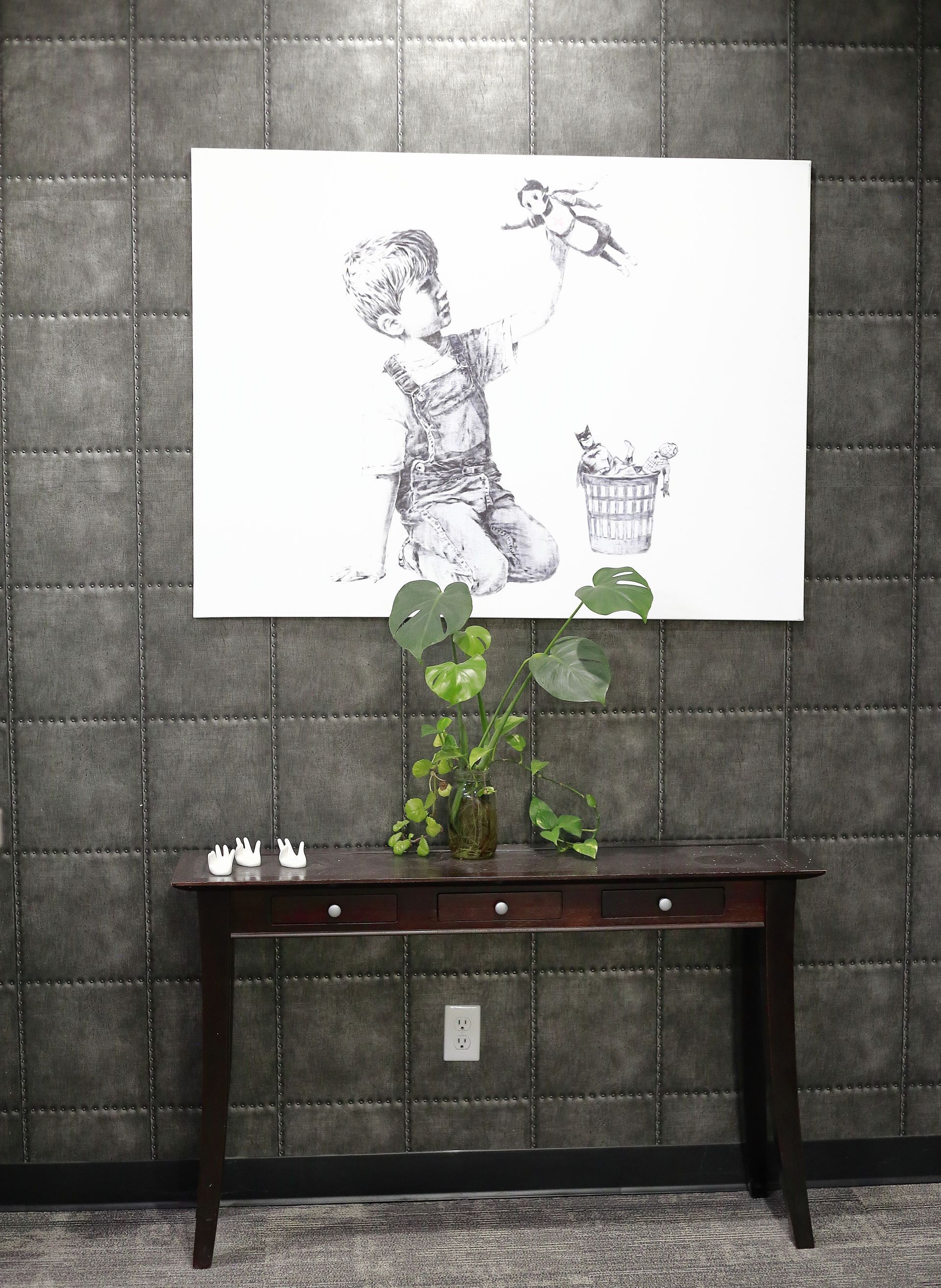 A painting on a wall above a table with a plant in front of it