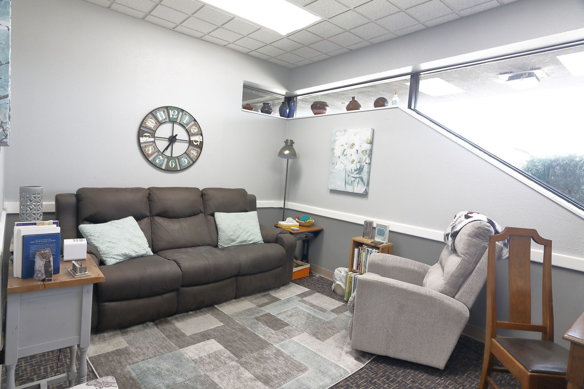 A living room with a couch , chair and clock on the wall.