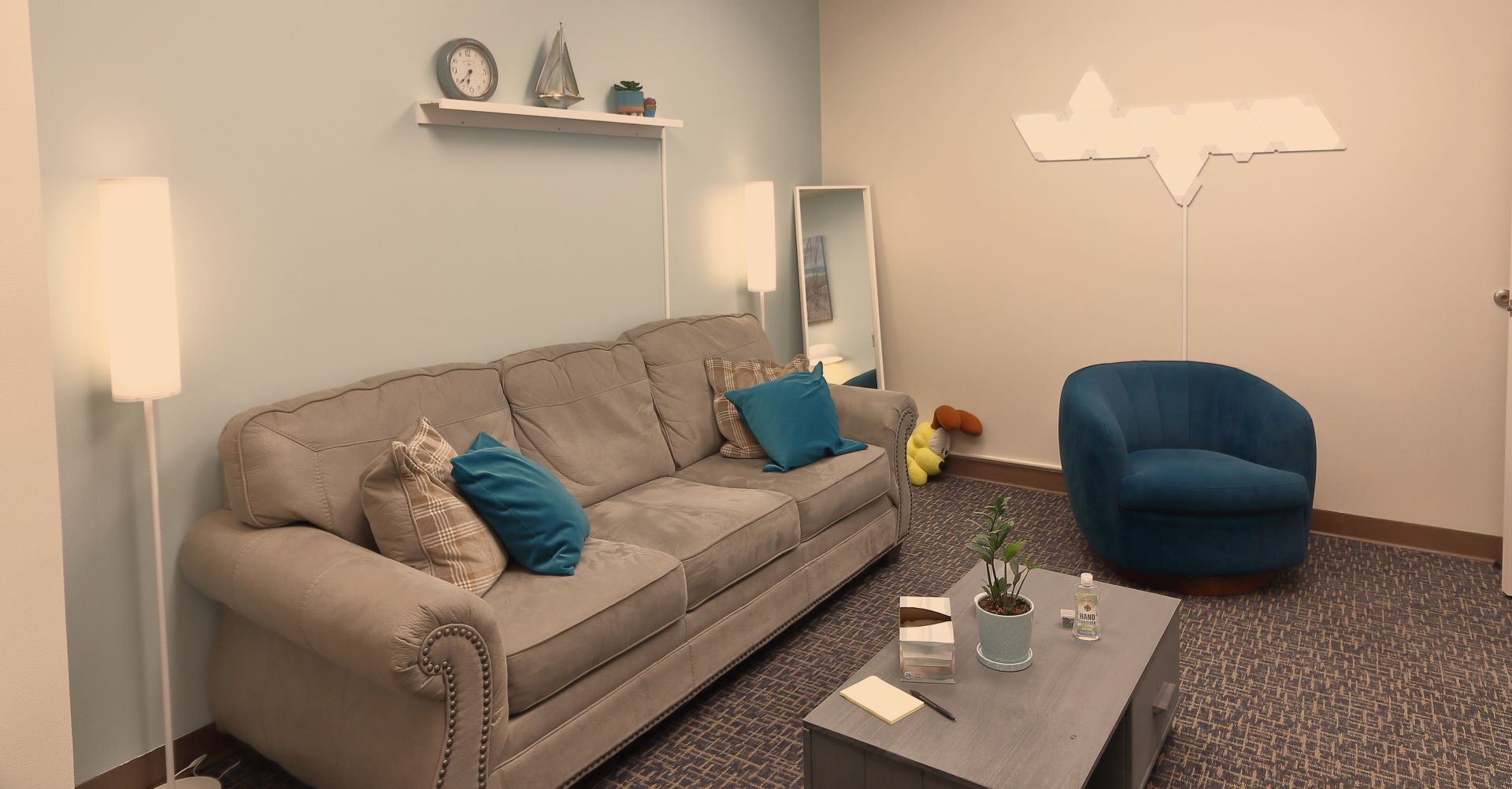 A living room with a couch , chair , coffee table and mirror.