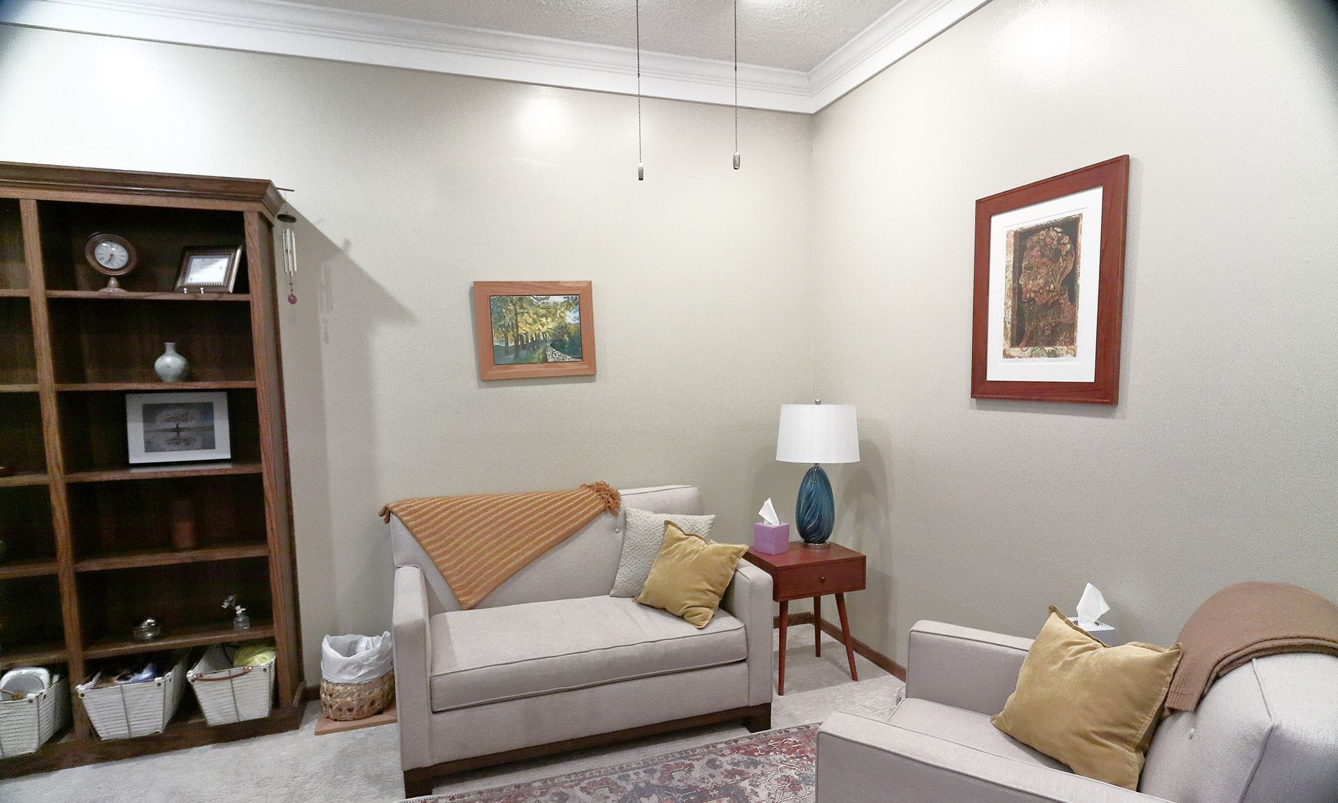 A living room in Southpark Psychology, 2100 facility with a couch, chair, and bookshelf. - Katy