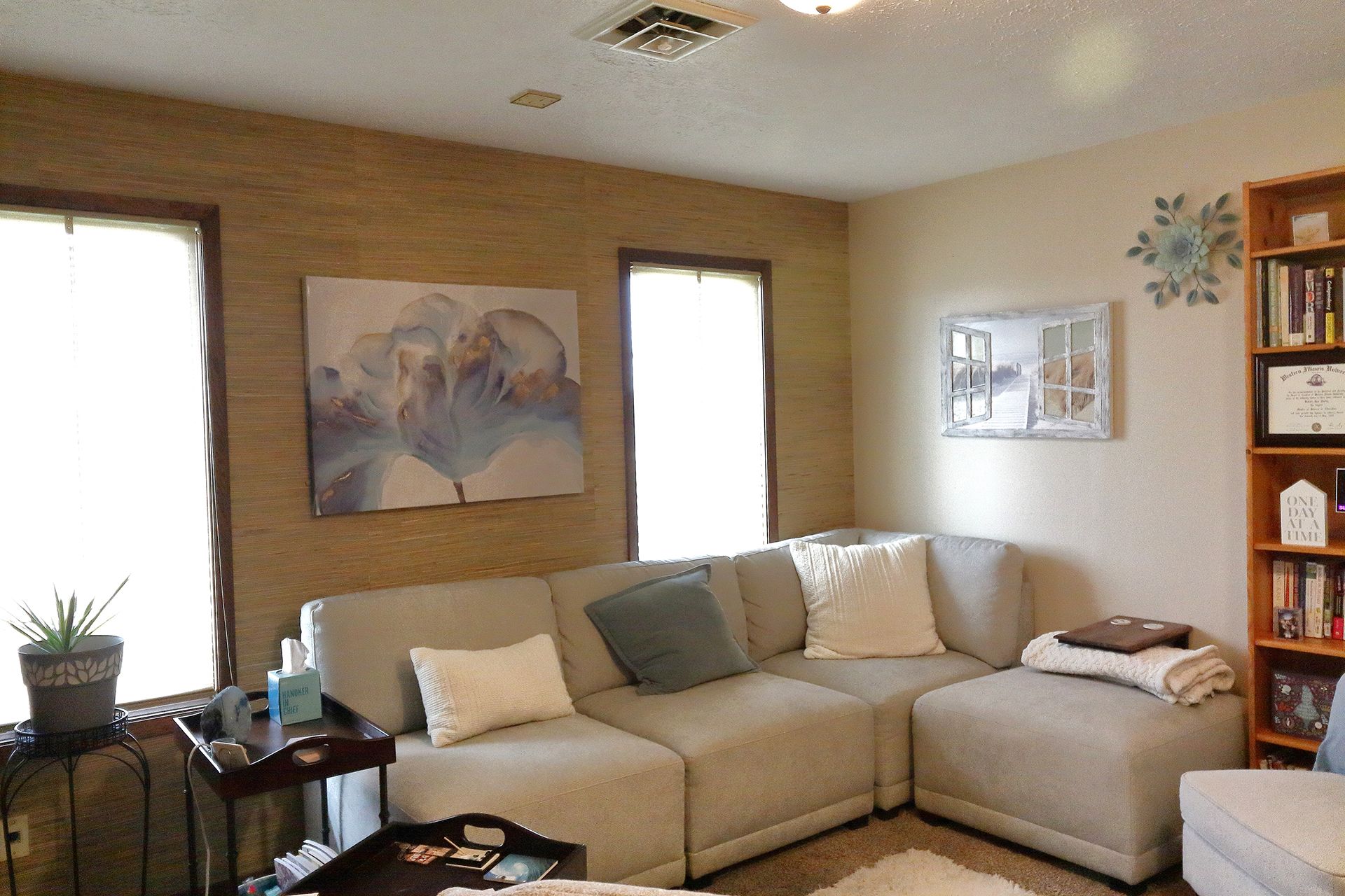 A living room with a sectional couch and bookshelves in Southpark Psychology, 2100 facility. - VO