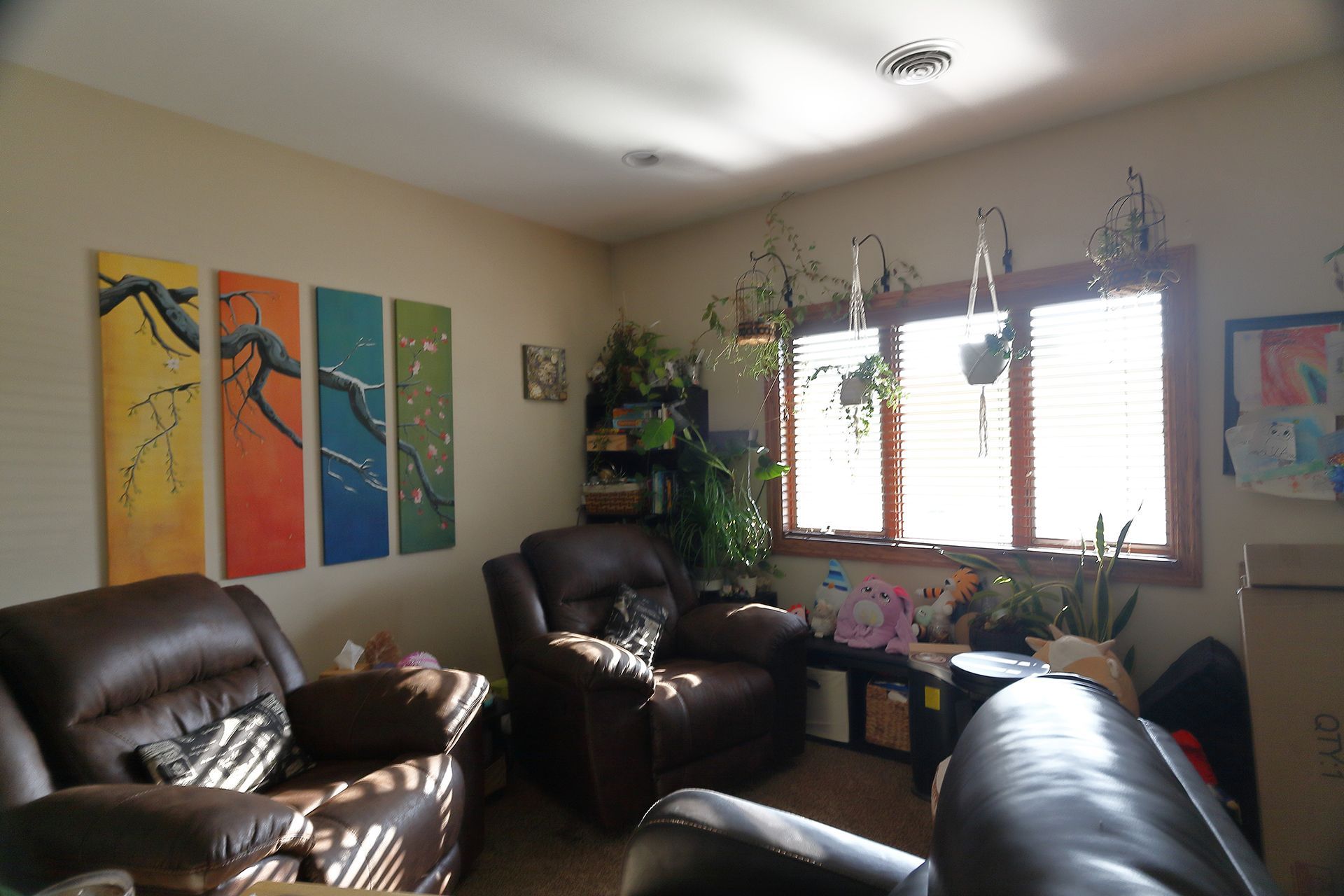 A living room with a lot of furniture and paintings on the wall. - Alex