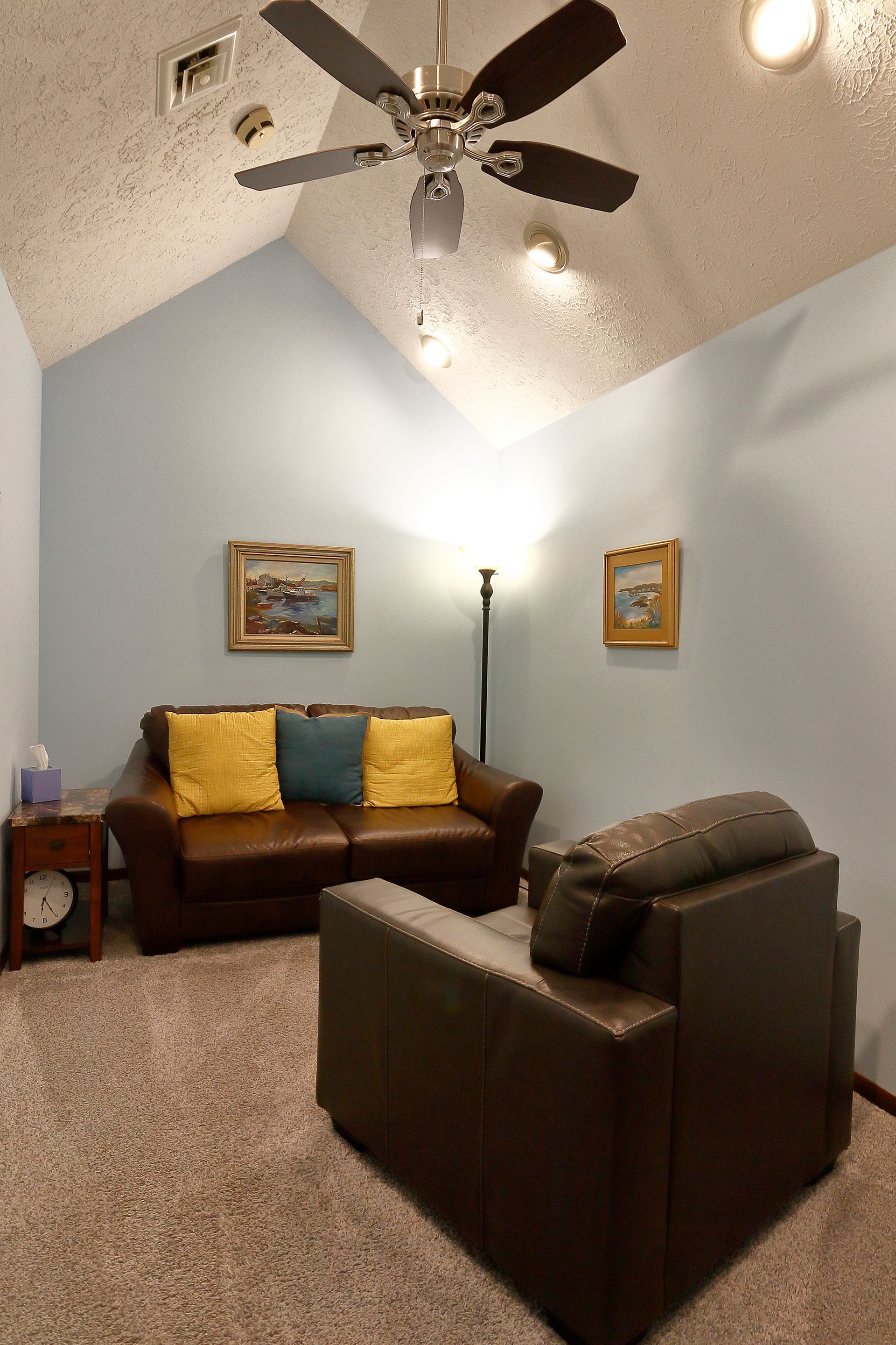 A living room in Southpark Psychology, 2100 facility with a couch, chair, lamp, and ceiling fan. - Frank