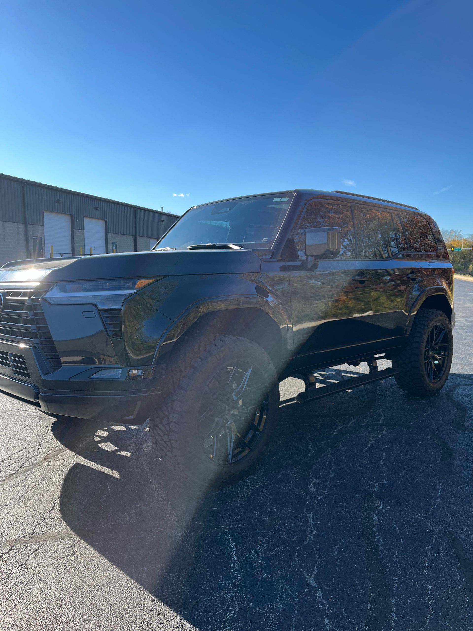 Black SUV parked outdoors on a sunny day beside an industrial building