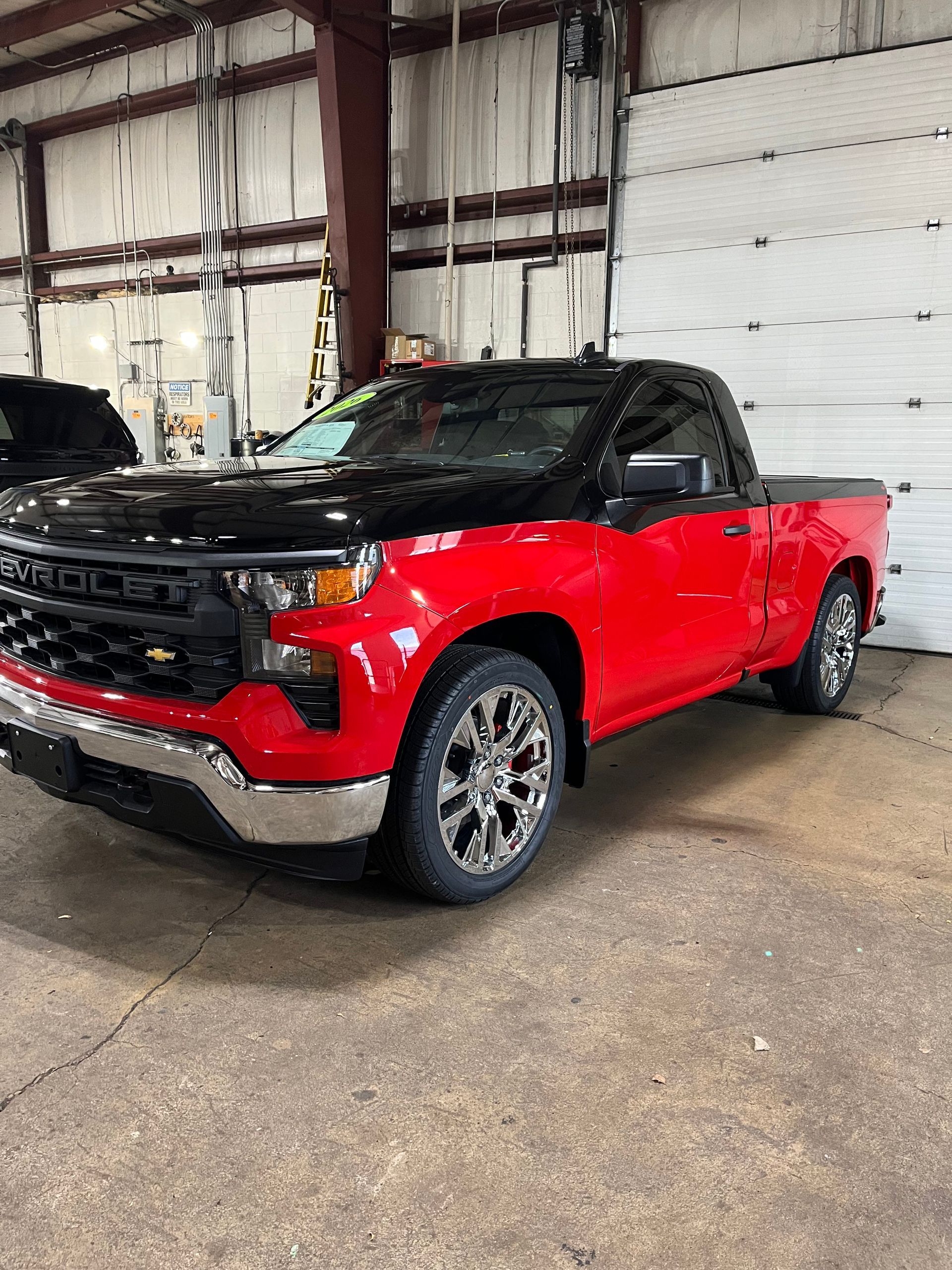 Red and black pickup truck parked indoors in a warehouse garage