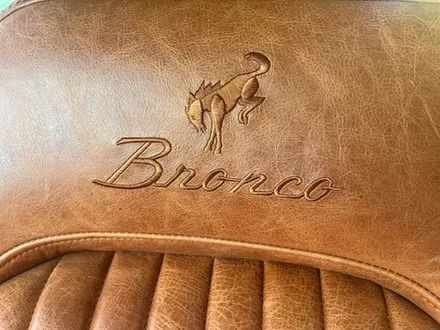Bronco logo embossed on tan leather with stitched seat detail
