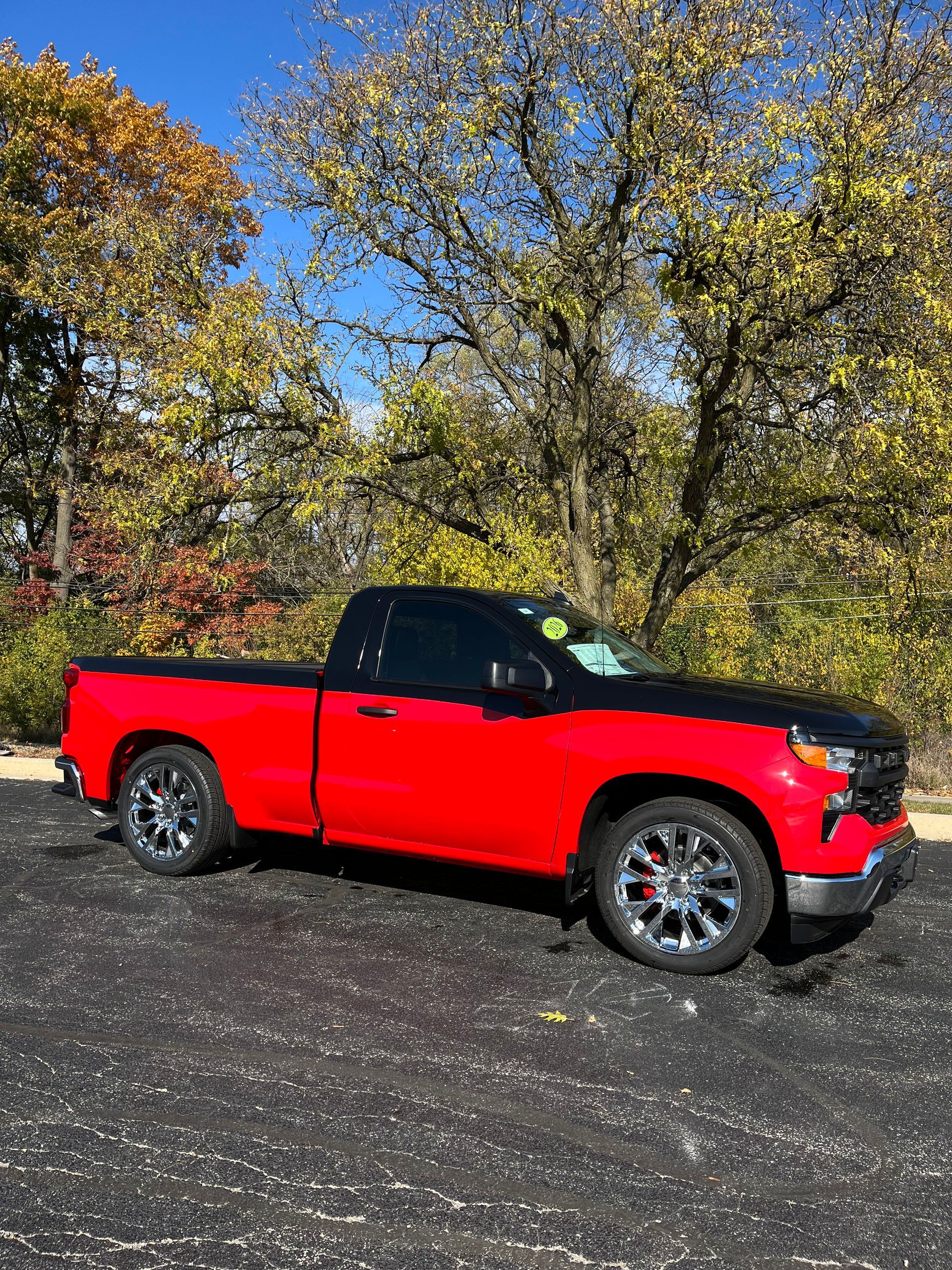 Red pickup truck parked on gravel in a wooded area
