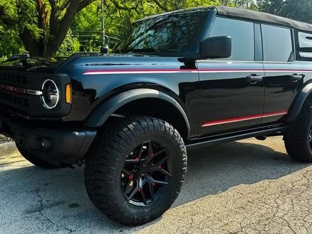 Black off-road SUV parked on a street, with lifted suspension, red accents, and tinted windows