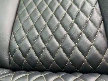 Close-up of black quilted leather upholstery with diamond stitching and light reflections