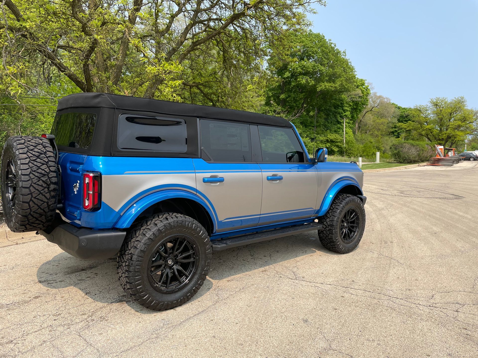 Blue and black off-road SUV parked on a gravel road with trees in the background