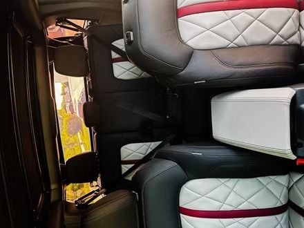 Interior of a vehicle with black-and-white quilted seats and a red accent stripe, viewed from the back seat