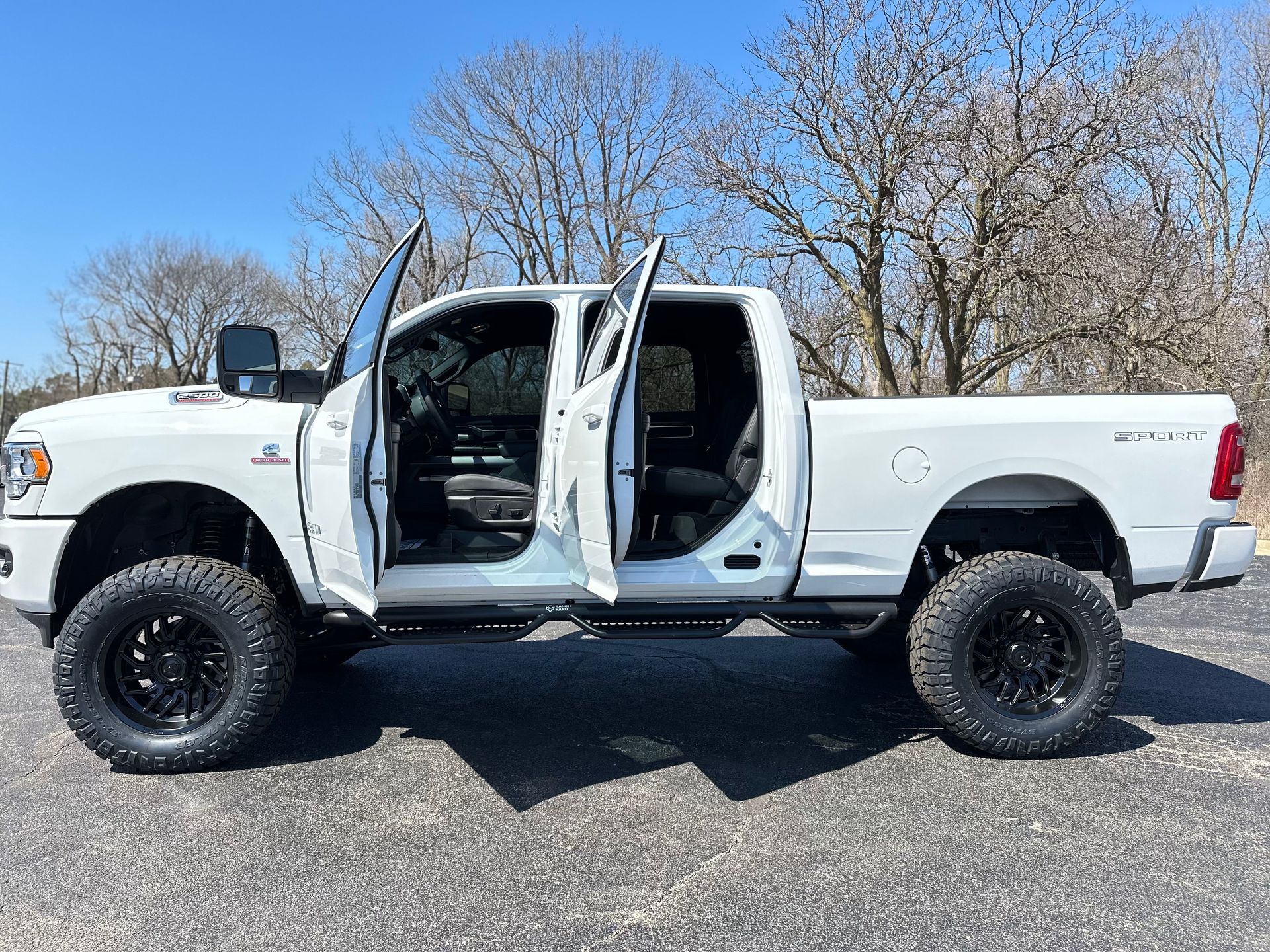 White lifted pickup truck with open doors parked outdoors on a sunny day