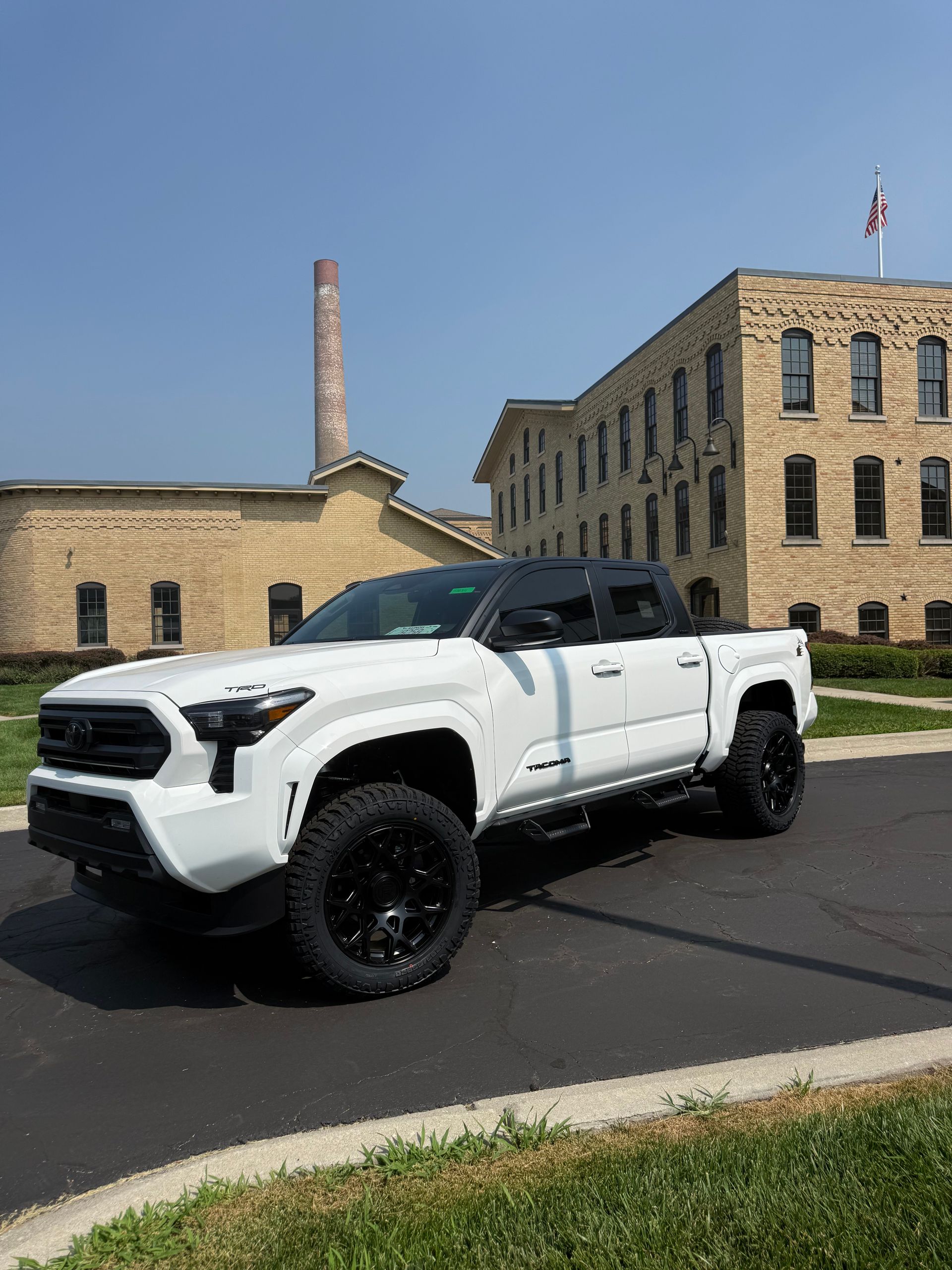 White pickup truck parked outside a stone building under a clear blue sky.
