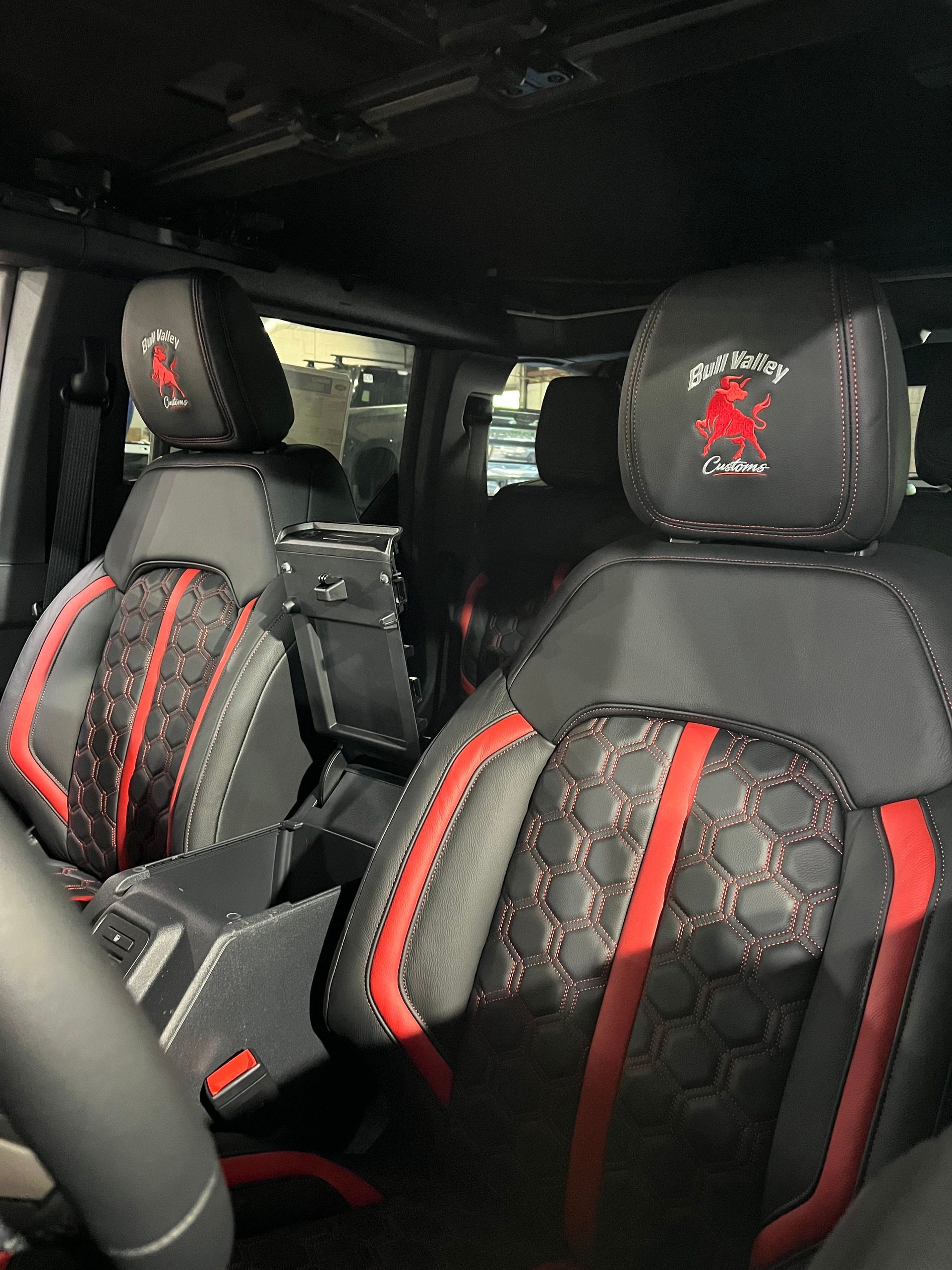 Car interior with black seats featuring red accents and patterned seat covers.