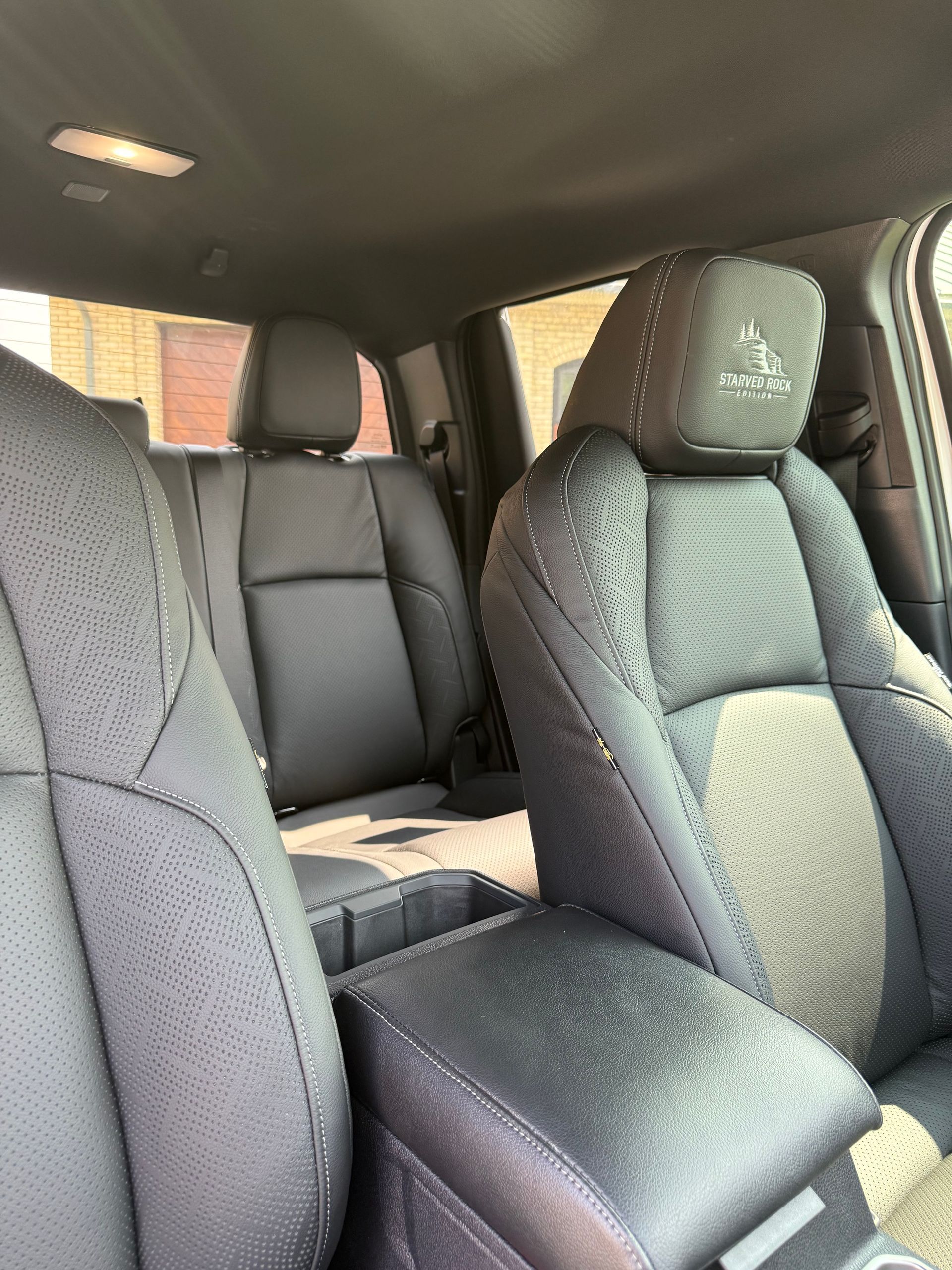 Black car interior with front seats and center console, viewed from the back seat.