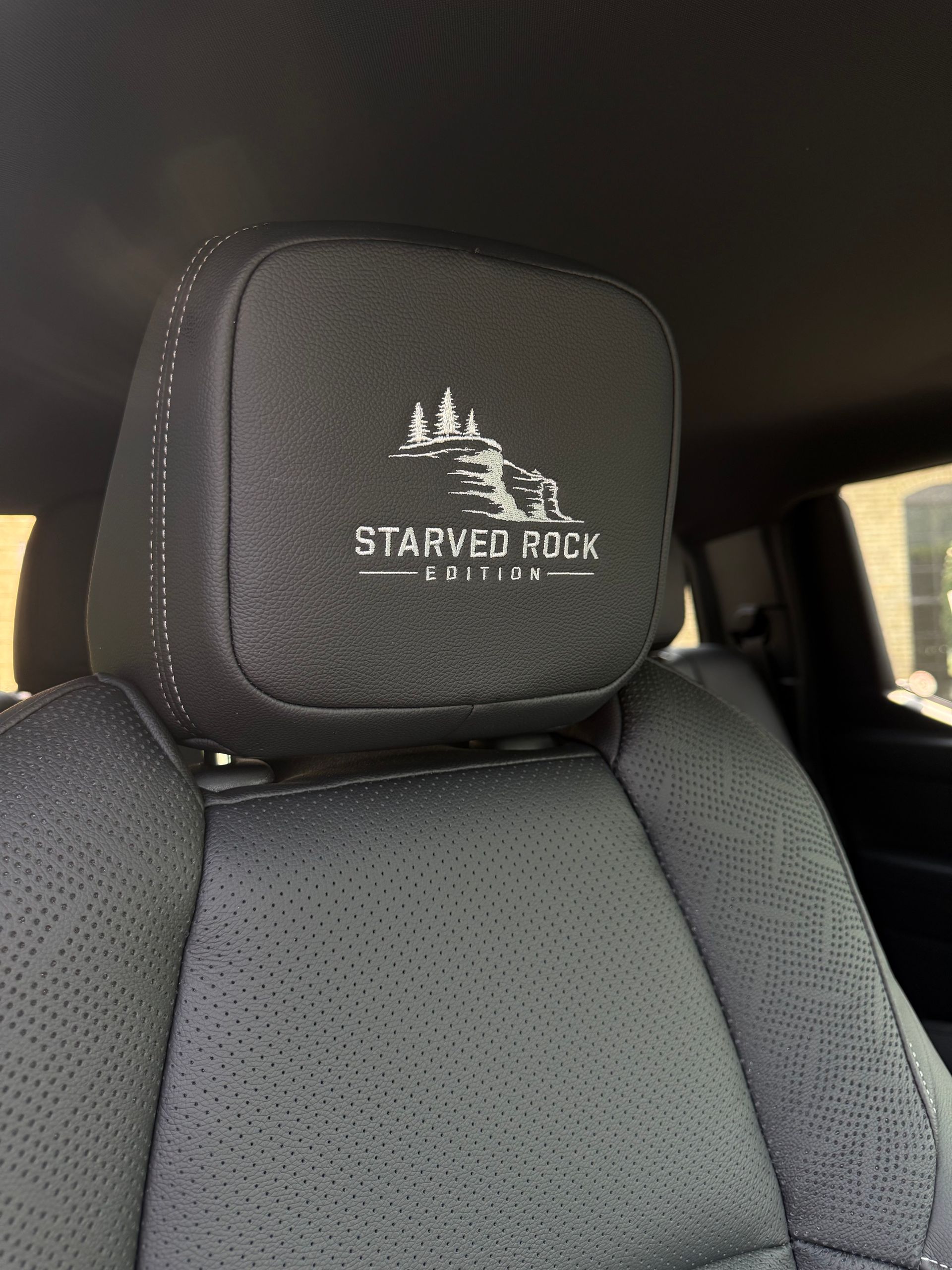Front car seat with black Starved Rock logo headrest and fabric upholstery