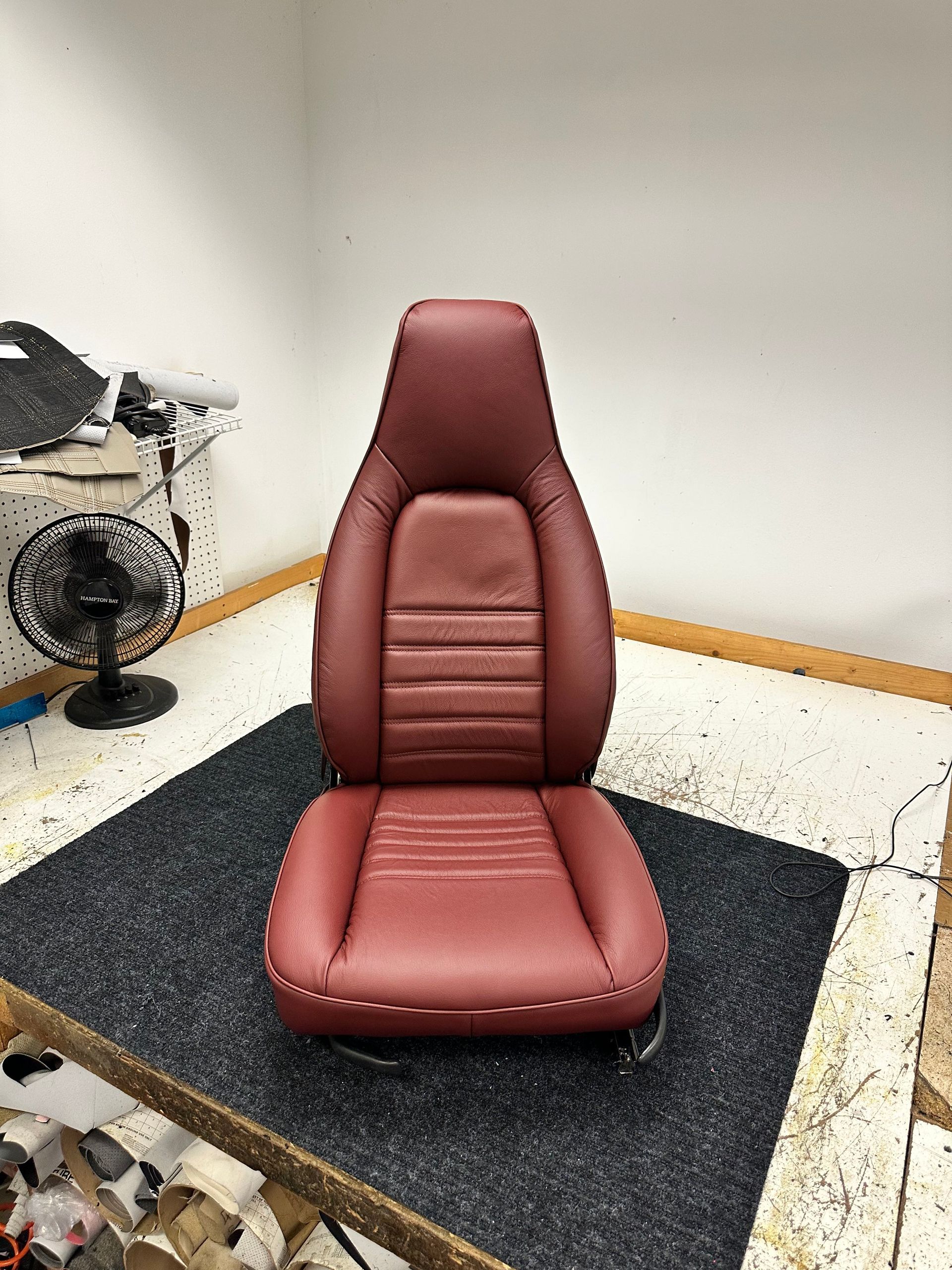 Maroon car seat on a black rug in a small room