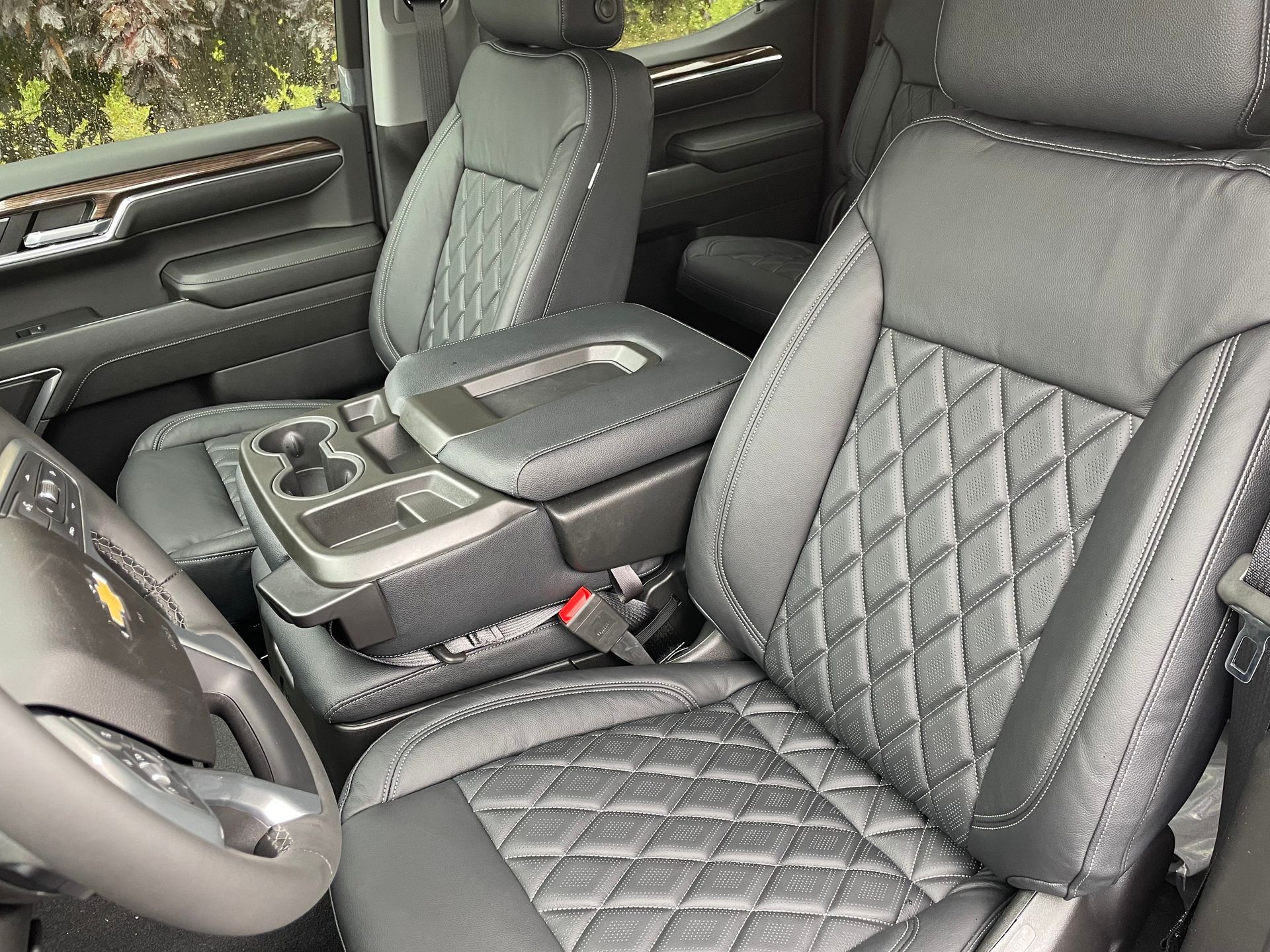 Luxury car interior with quilted gray leather seats, center console, and steering wheel.
