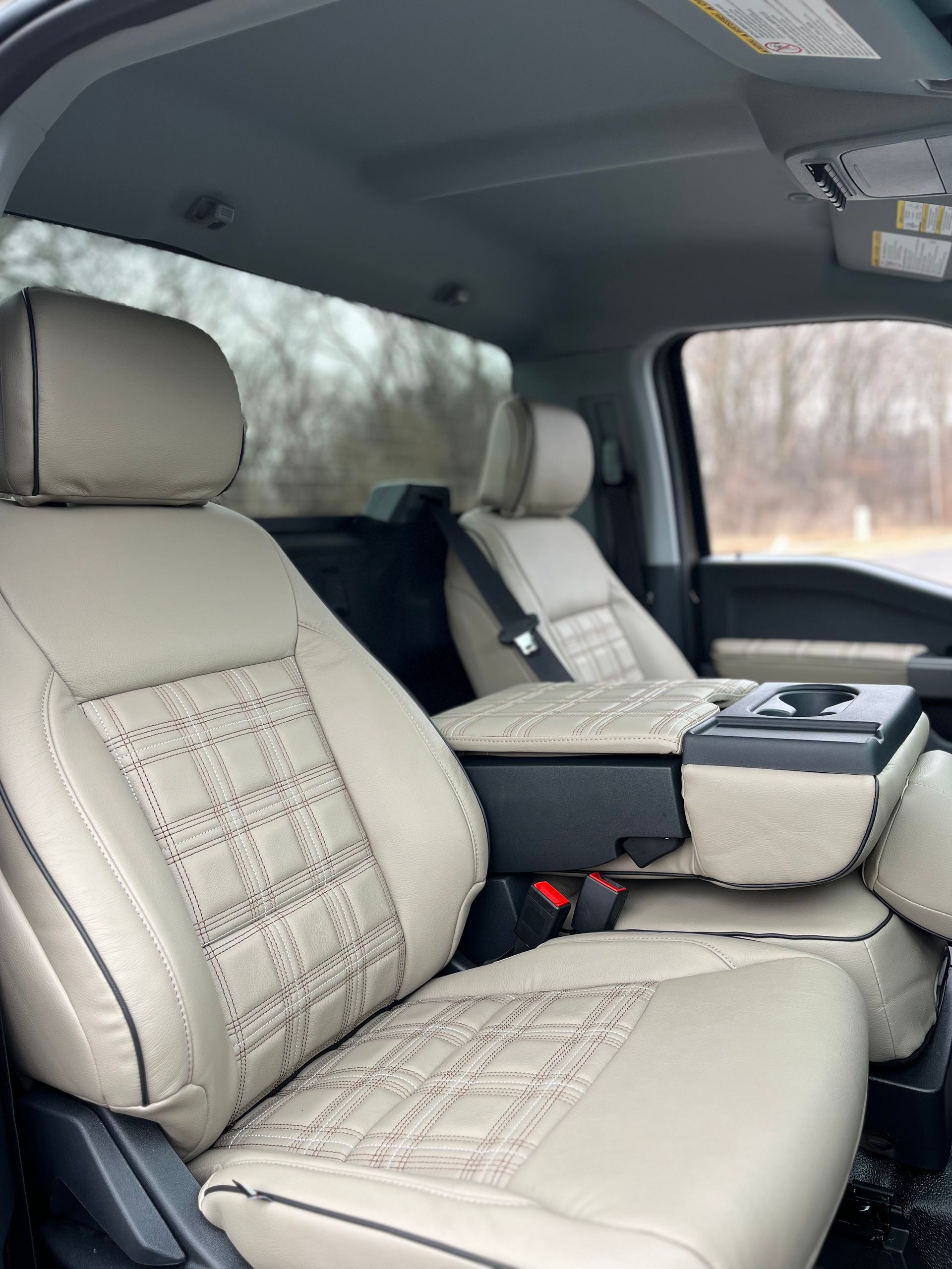 Light gray leather truck interior with patterned seats and center console, viewed from the rear passenger side