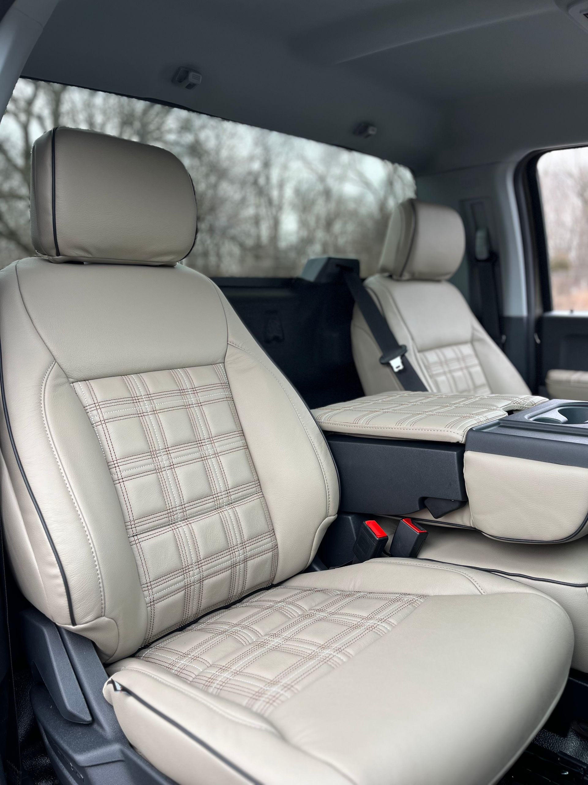 Beige car interior with front seats covered in patterned seat covers and a center console.
