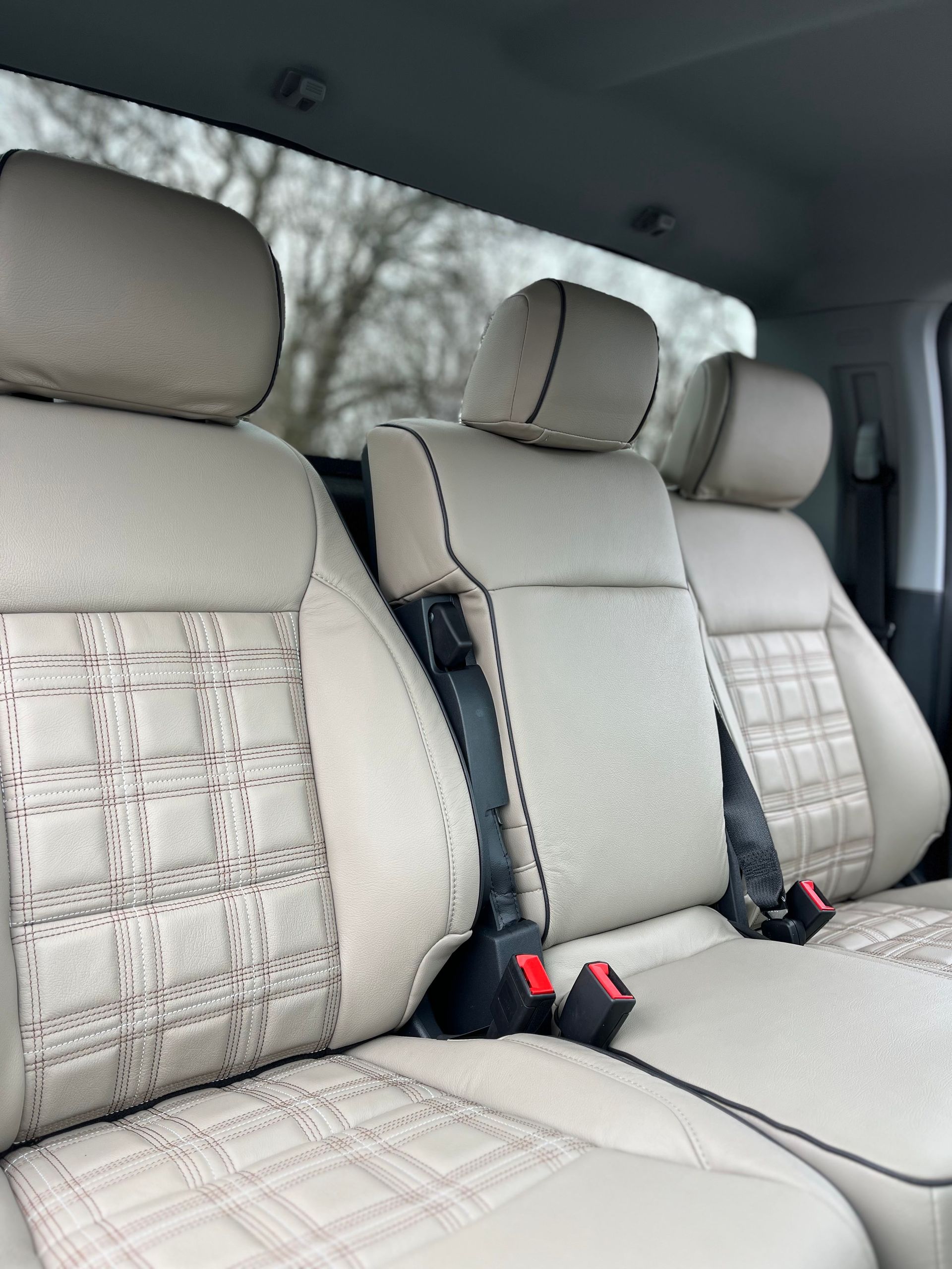 Light beige car back seat with three headrests and patterned upholstery