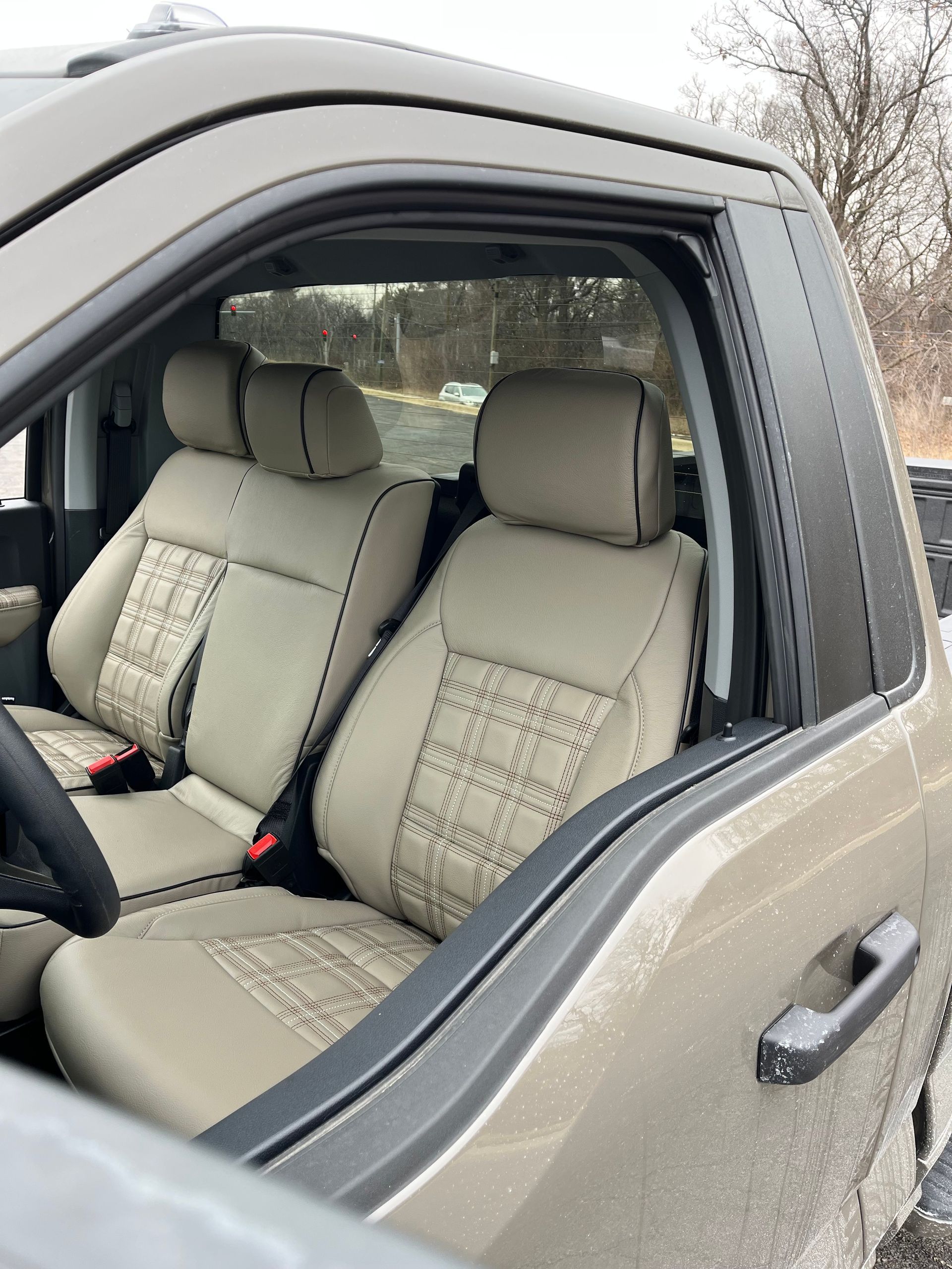 Car interior with beige seats and a partially open window, viewed from outside.
