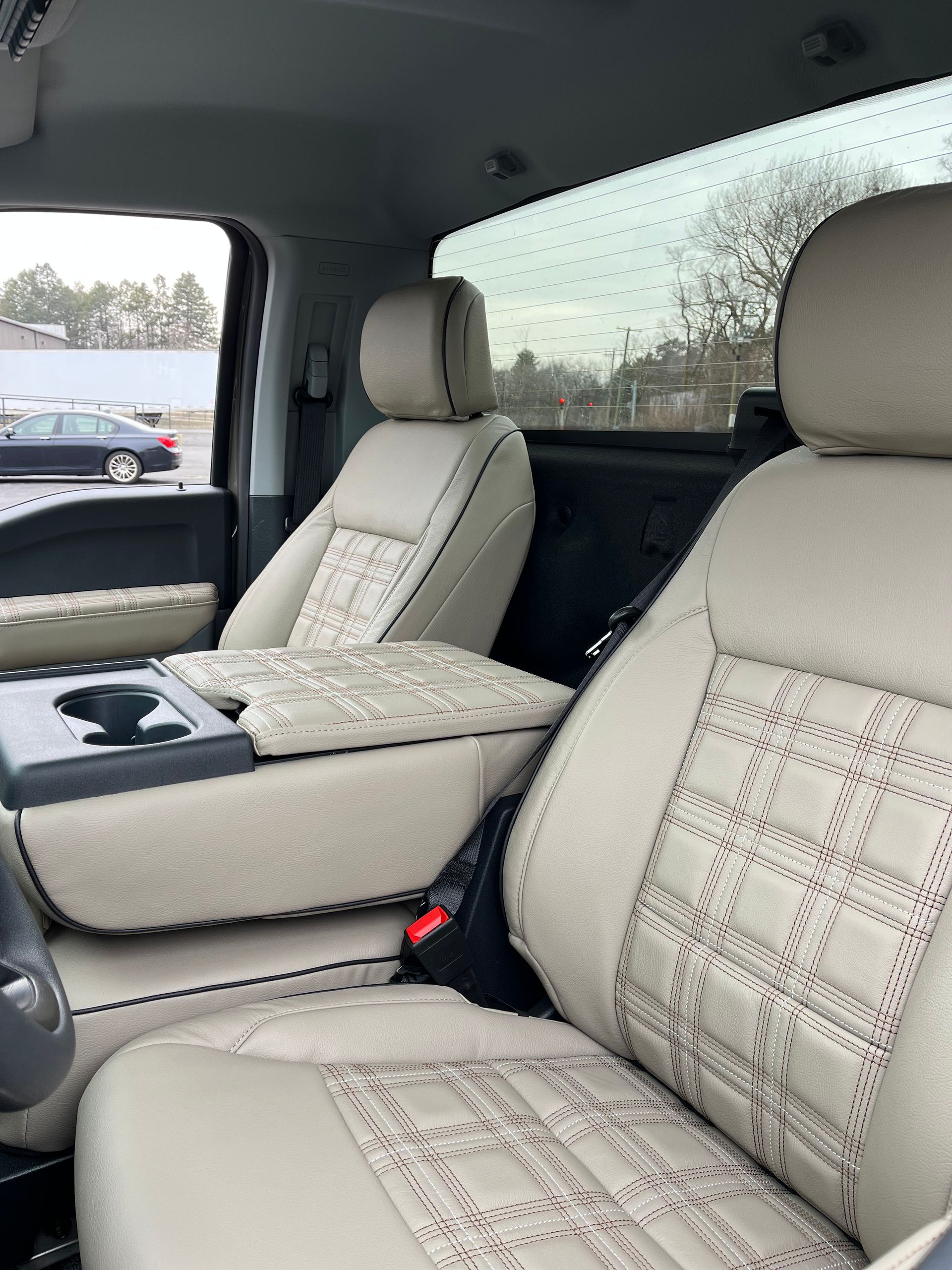 Interior of a car with beige plaid seats and center console, viewed from the front passenger side