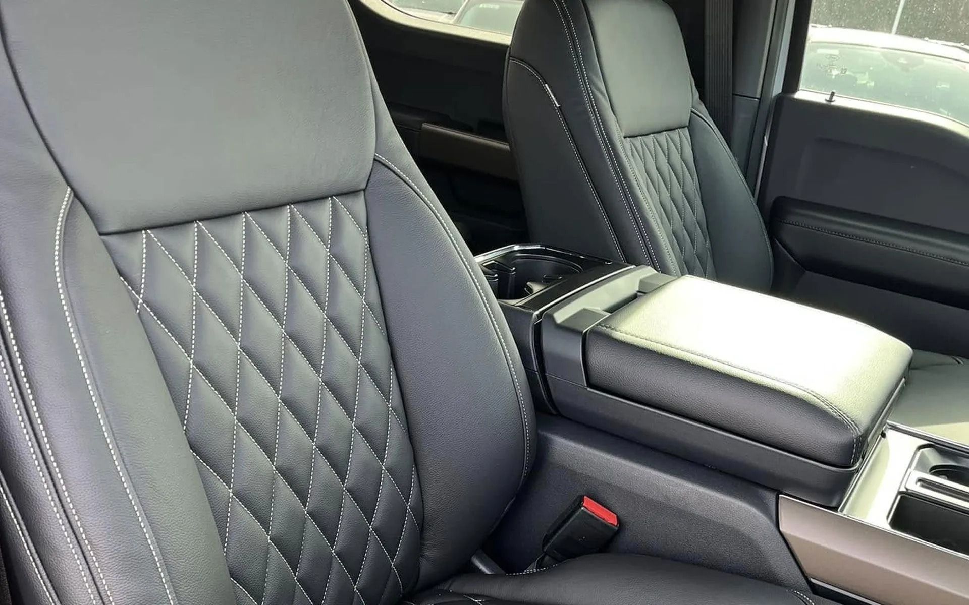 Gray leather car interior with diamond-stitched seats and a center console armrest.