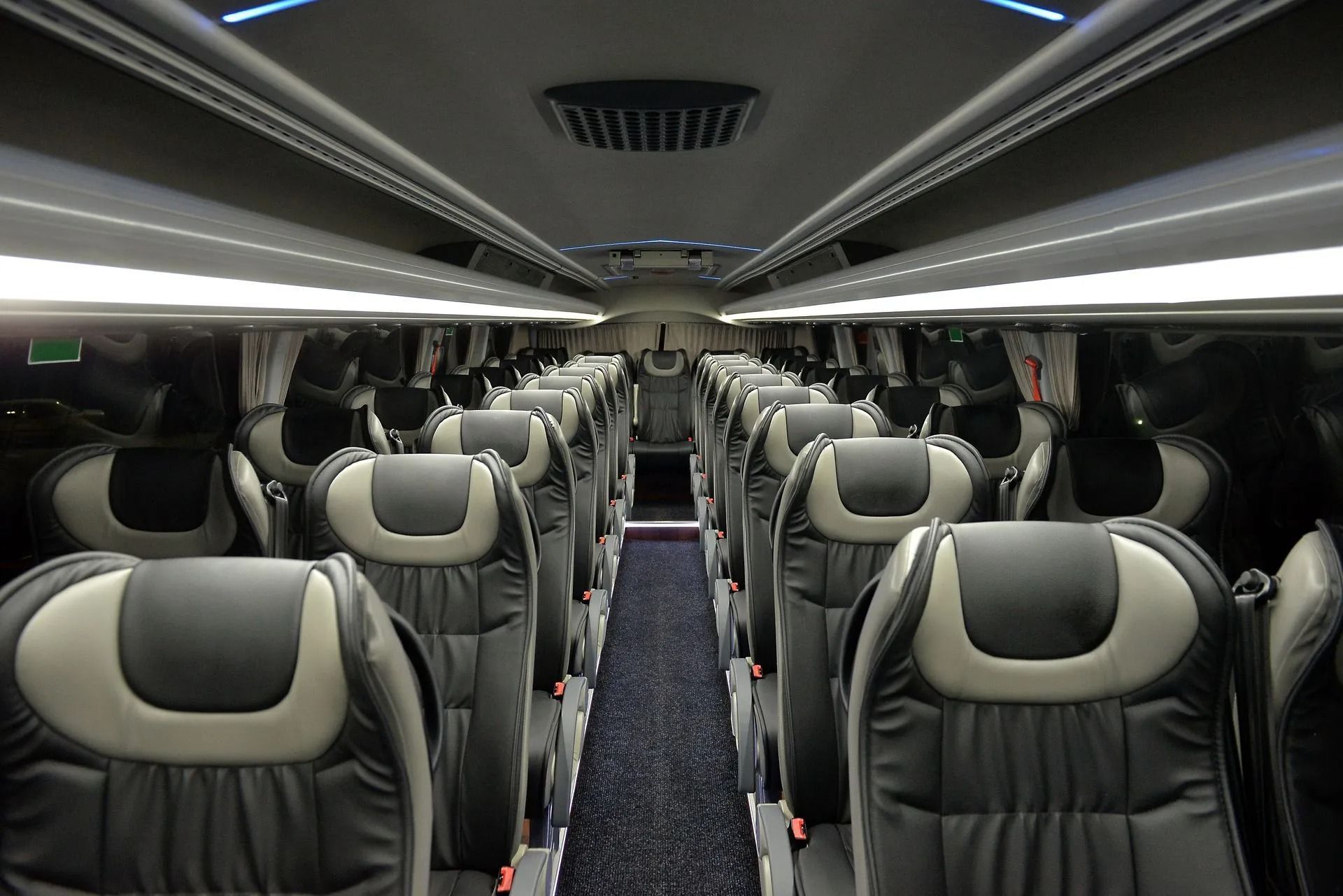 Empty bus interior with rows of gray seats and overhead lights in a modern coach