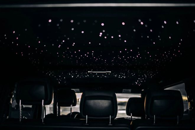 Empty theater with rows of seats under a dark ceiling lit by many small star-like lights