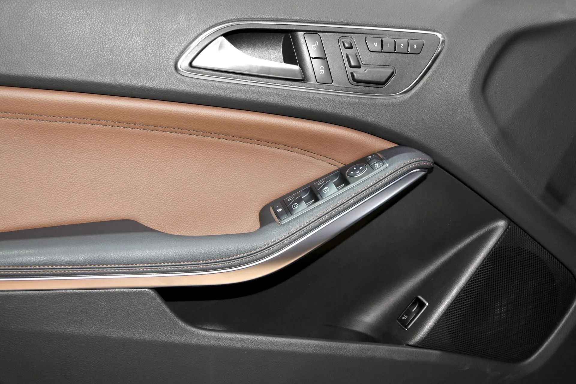 Car interior door panel with brown and black trim and silver window controls