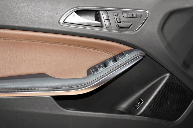Car interior door panel with brown and black trim and silver window controls