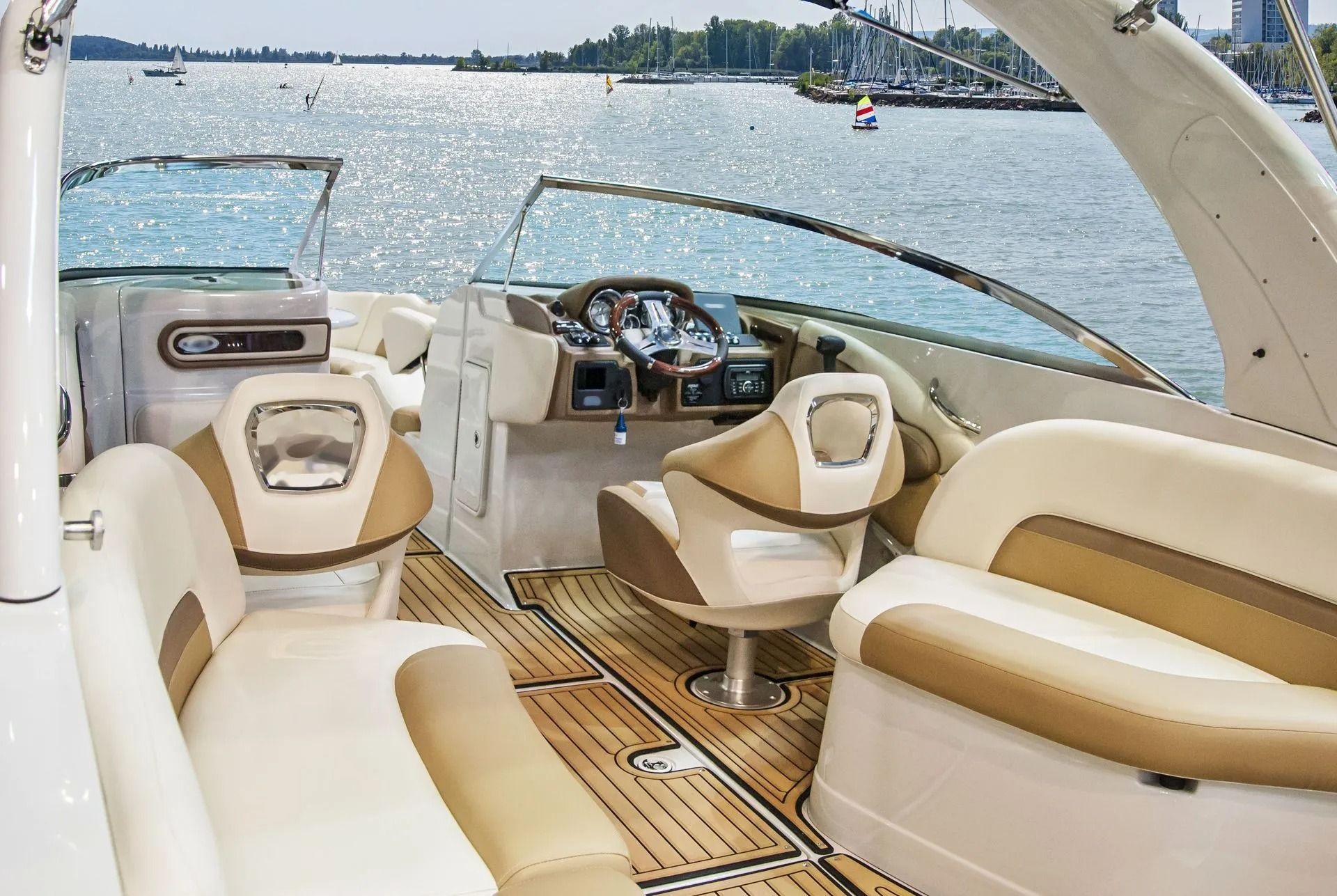 Boat cockpit with tan seating and wood deck overlooking a sunny lake