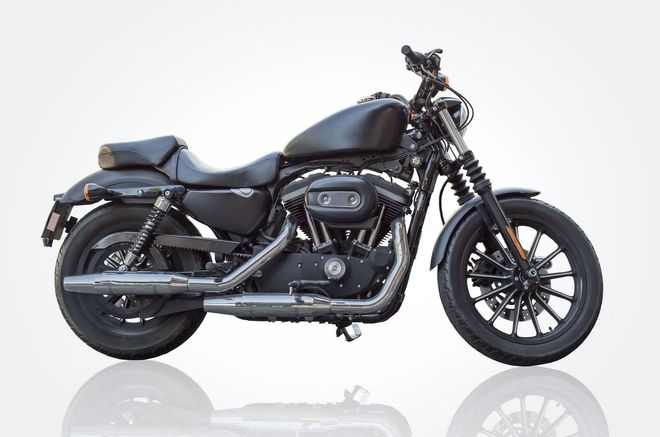 Black cruiser motorcycle on a white background, side view with chrome details and reflection