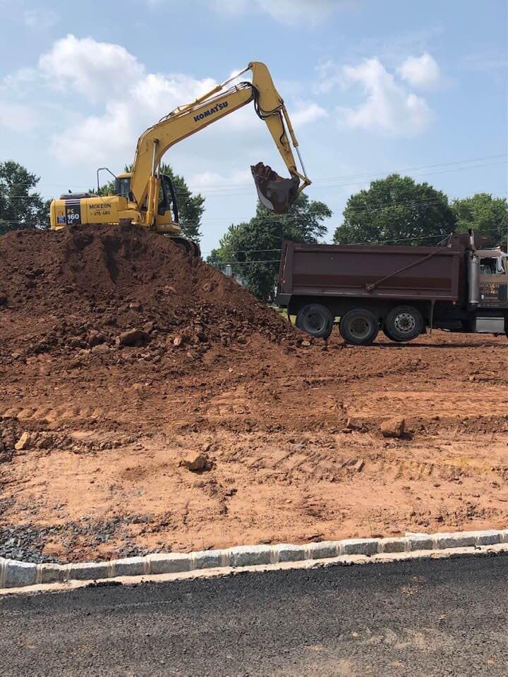 A yellow excavator is loading dirt into a dump truck.